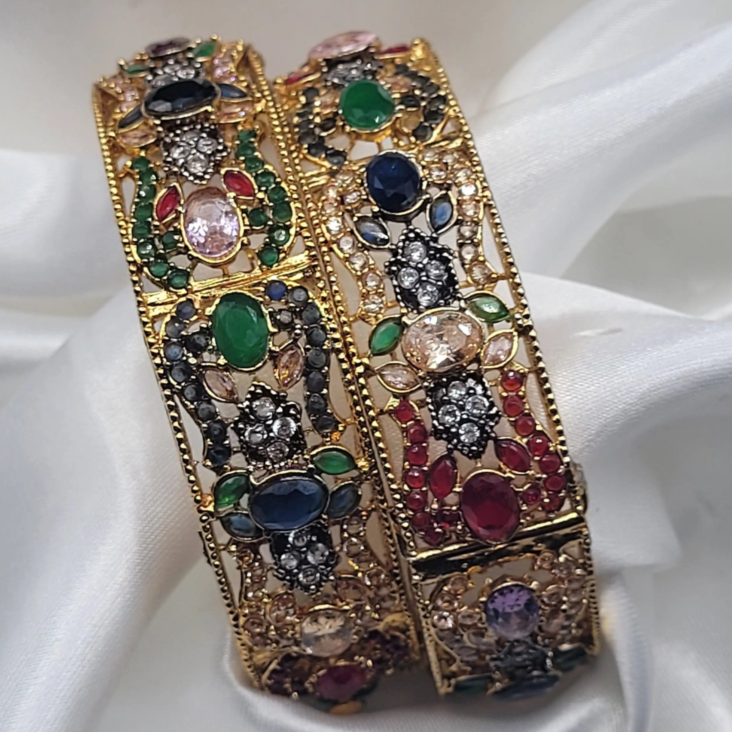 Festive gold bangles with red, green, blue, and clear stones – top view