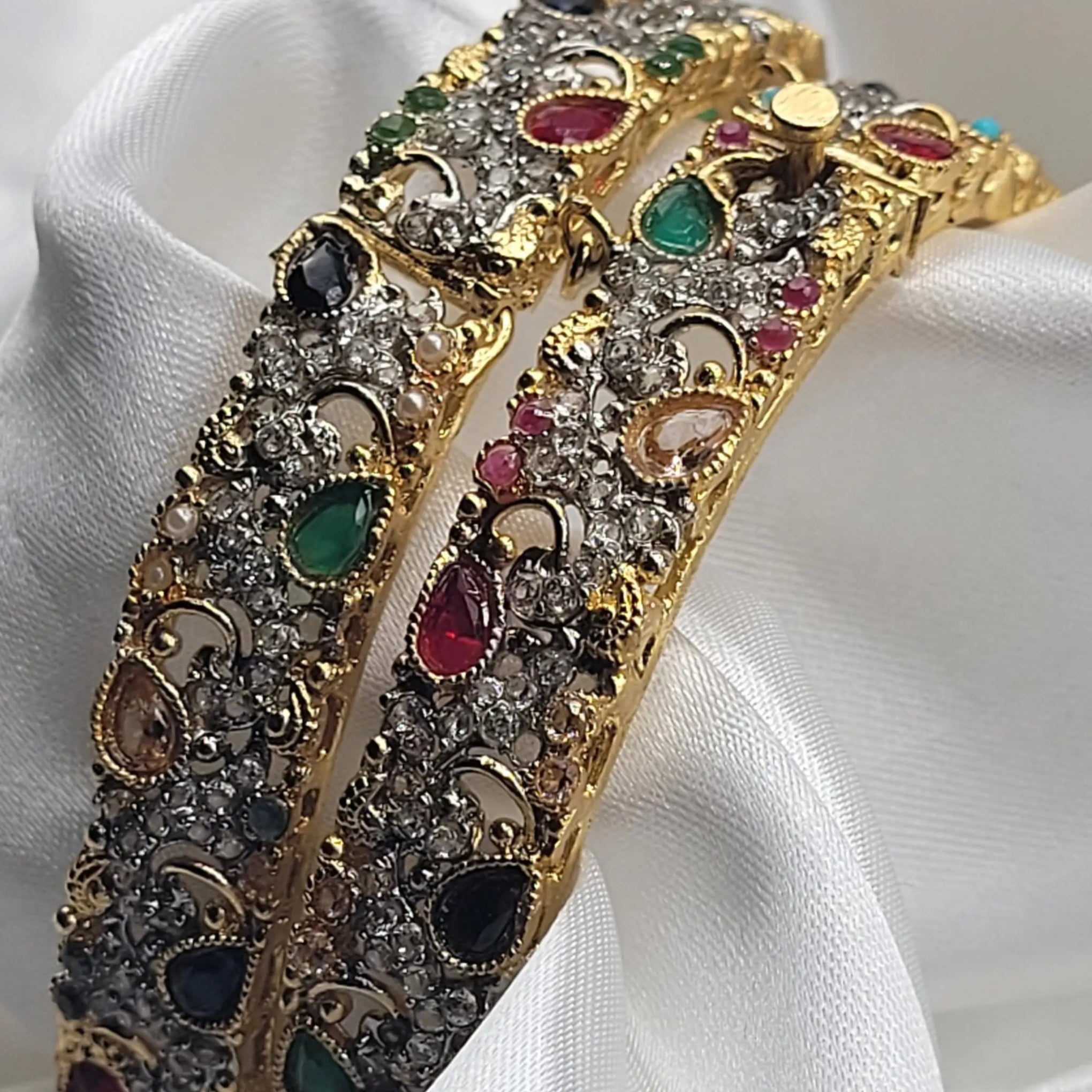 Close-up of multicolor teardrop bangles with textured gold and CZ embellishments