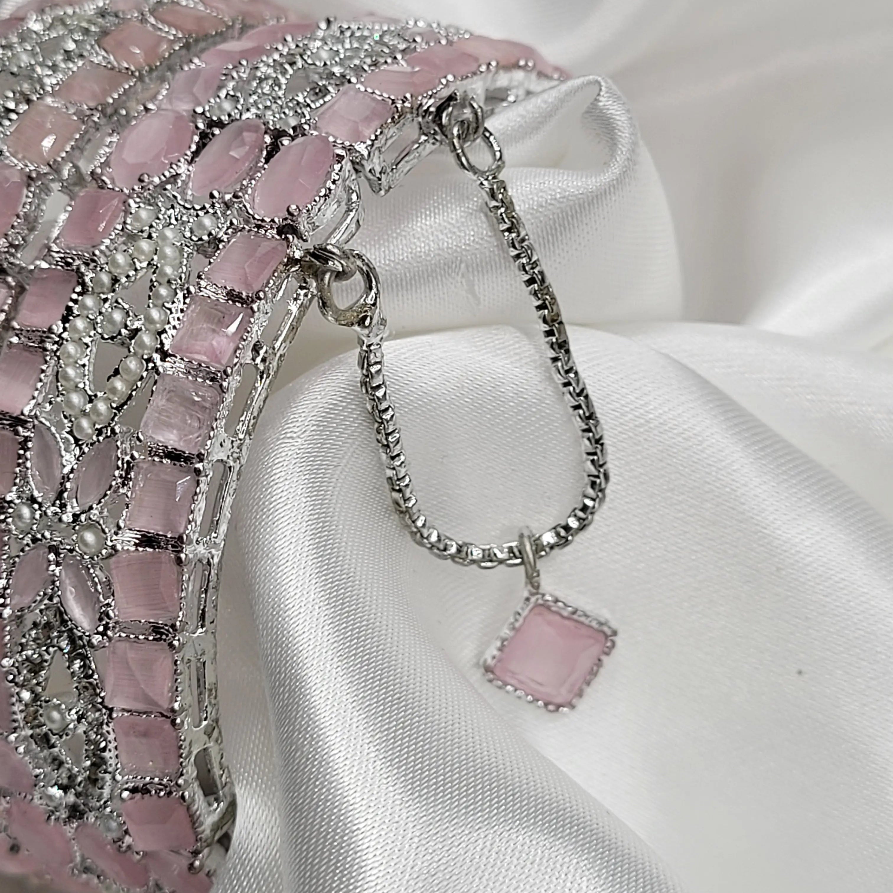 Close-up of pink square stone and CZ crystal bangles – safety chain visible
