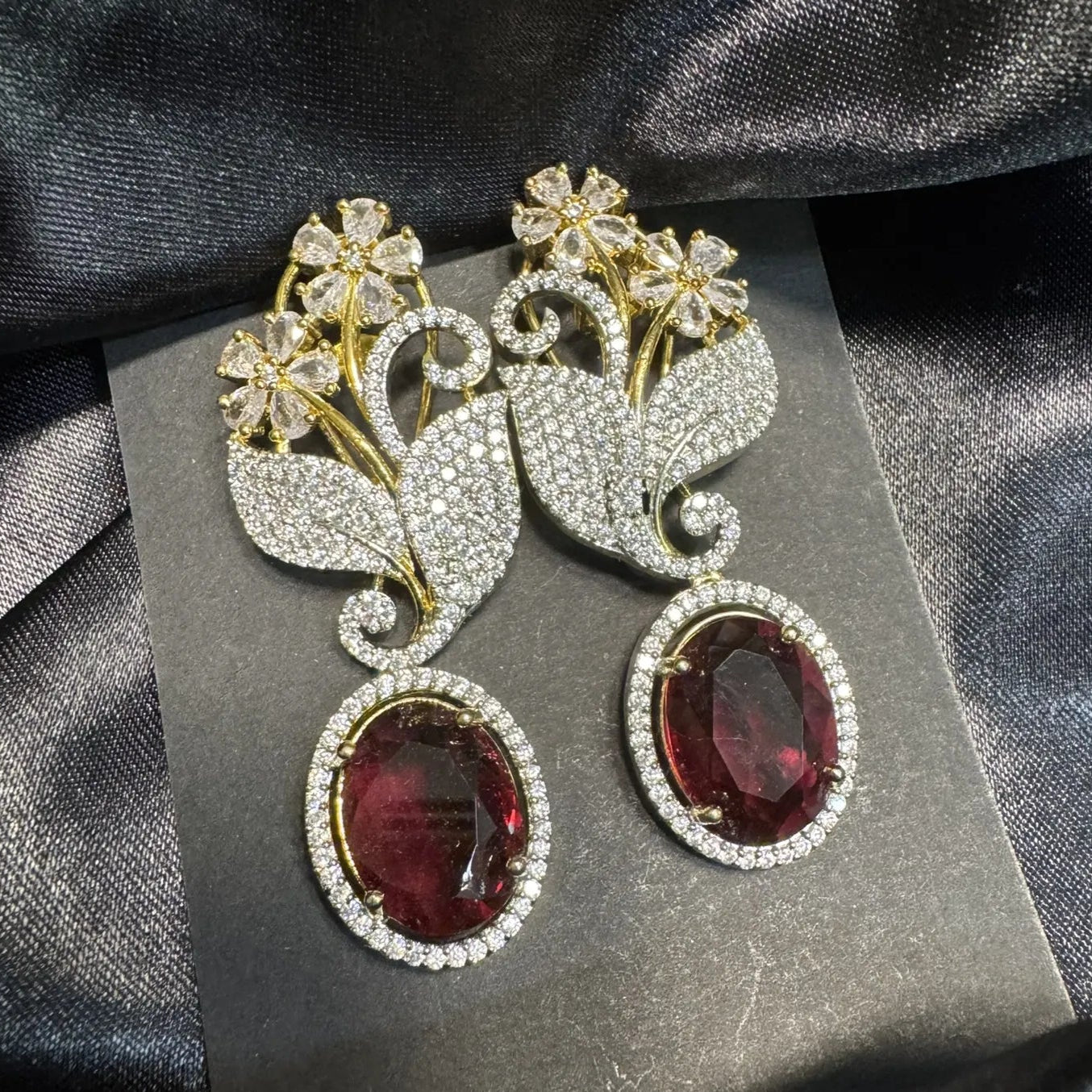 Ornate earrings with red gemstones on a dark fabric background