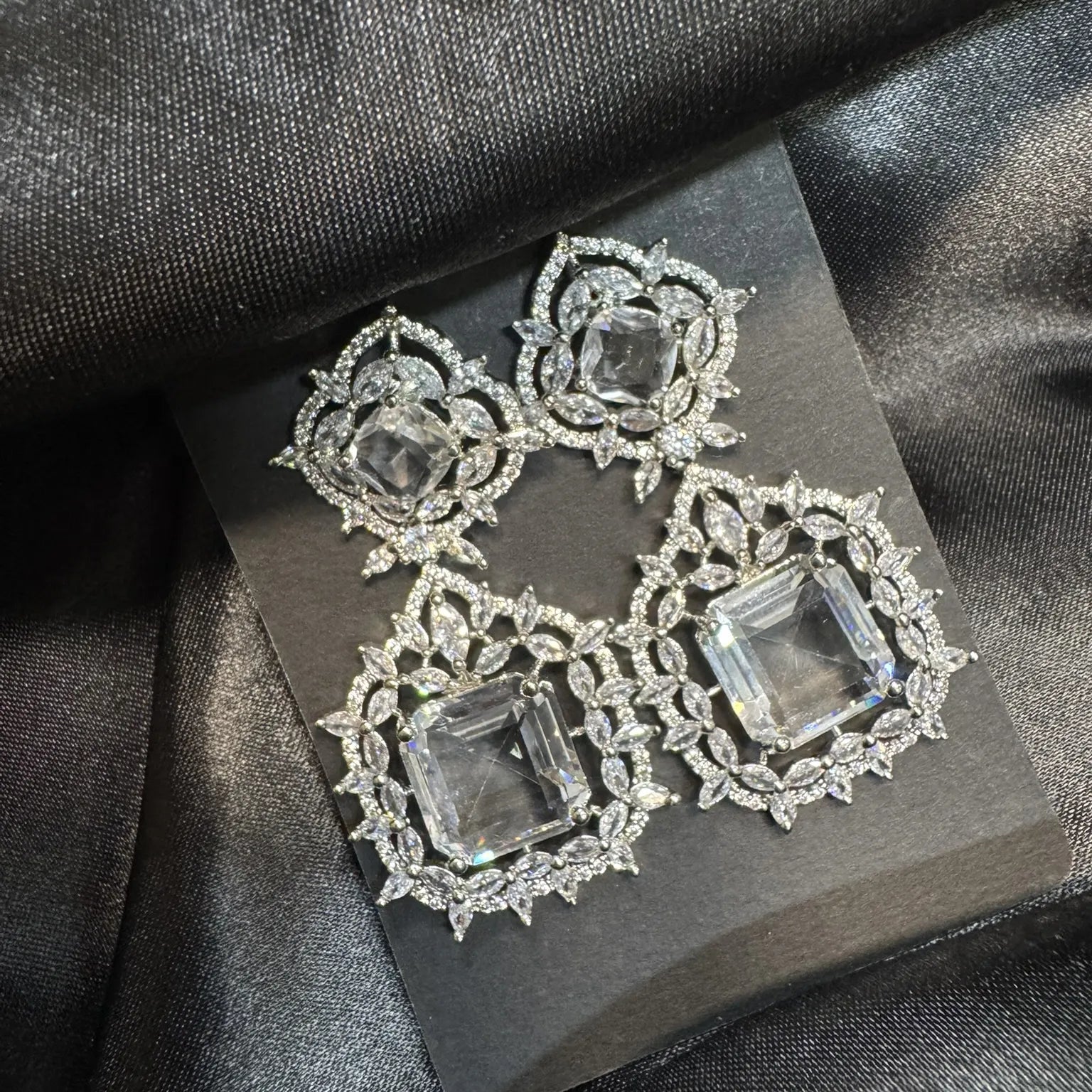 Ornate earrings with gemstones on a dark fabric background