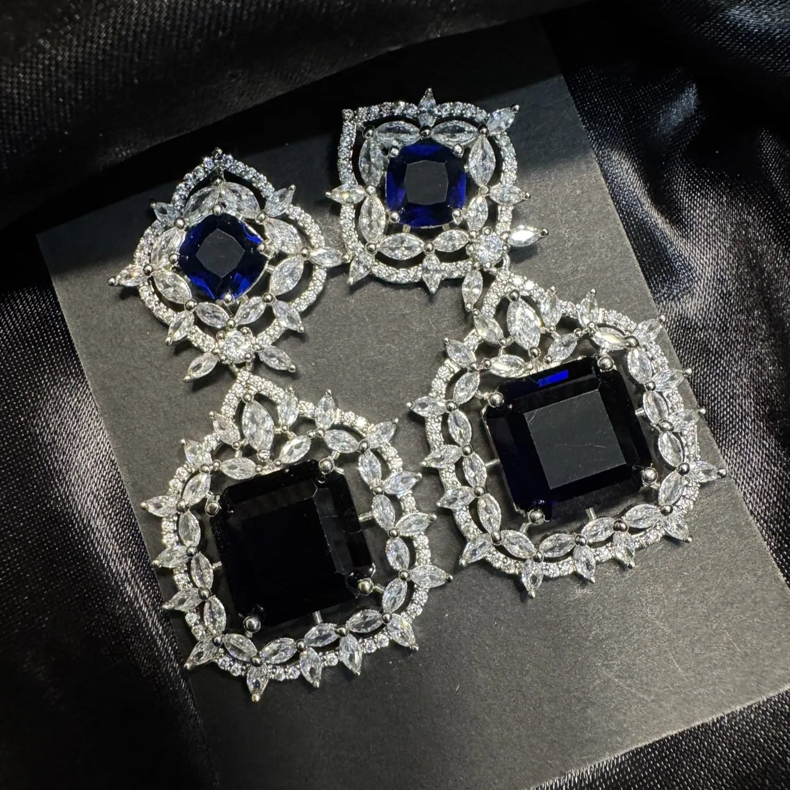 Pair of ornate earrings with blue gemstones on a black background