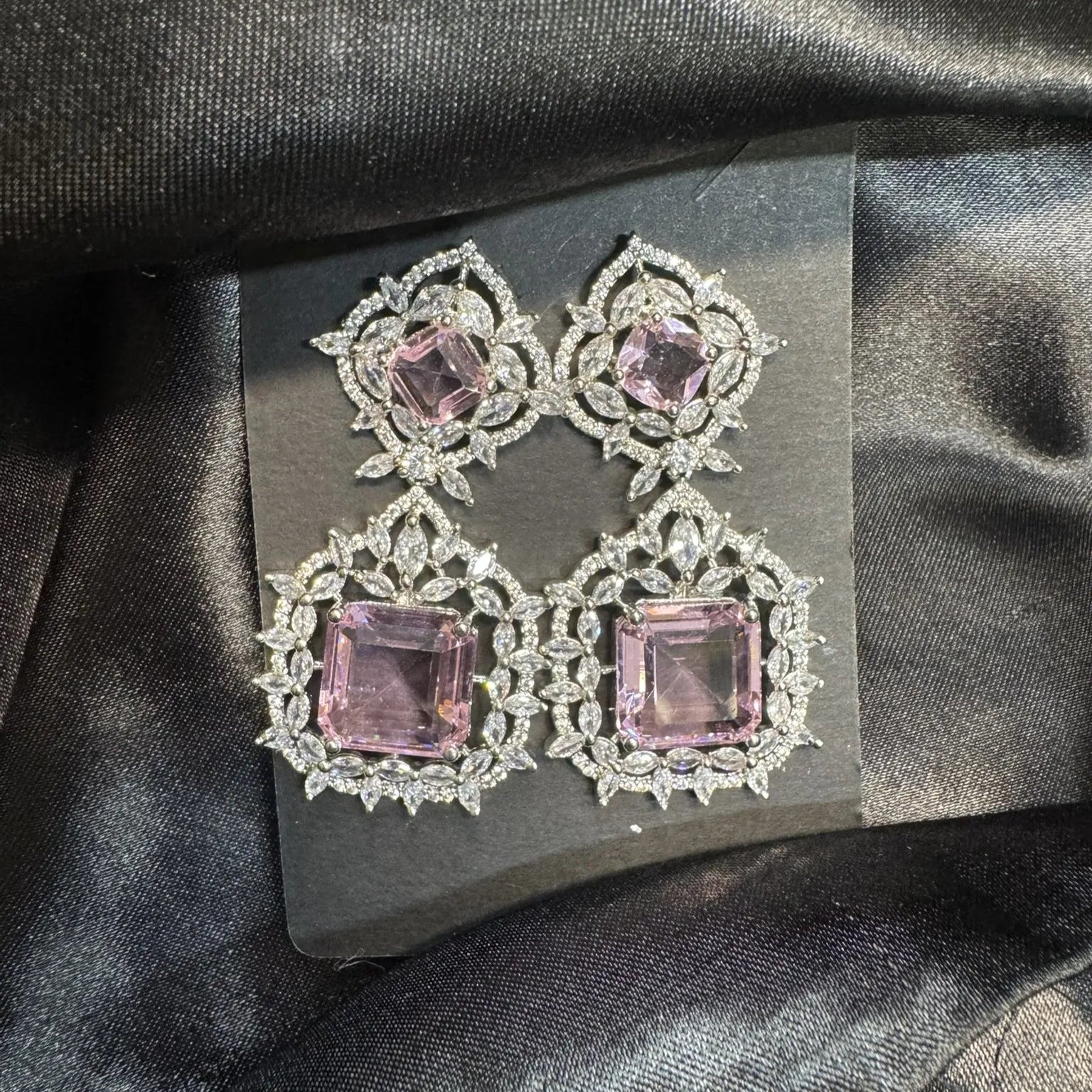 Pair of earrings with pink gemstones on a black satin background