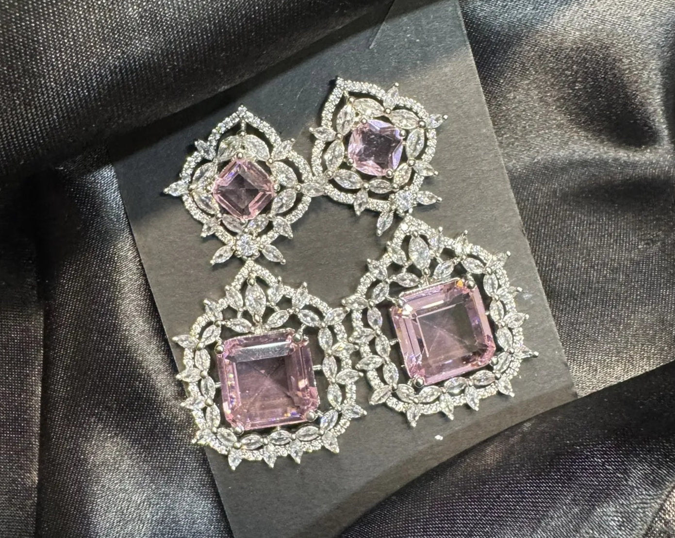 Pair of earrings with pink gemstones on a dark fabric background