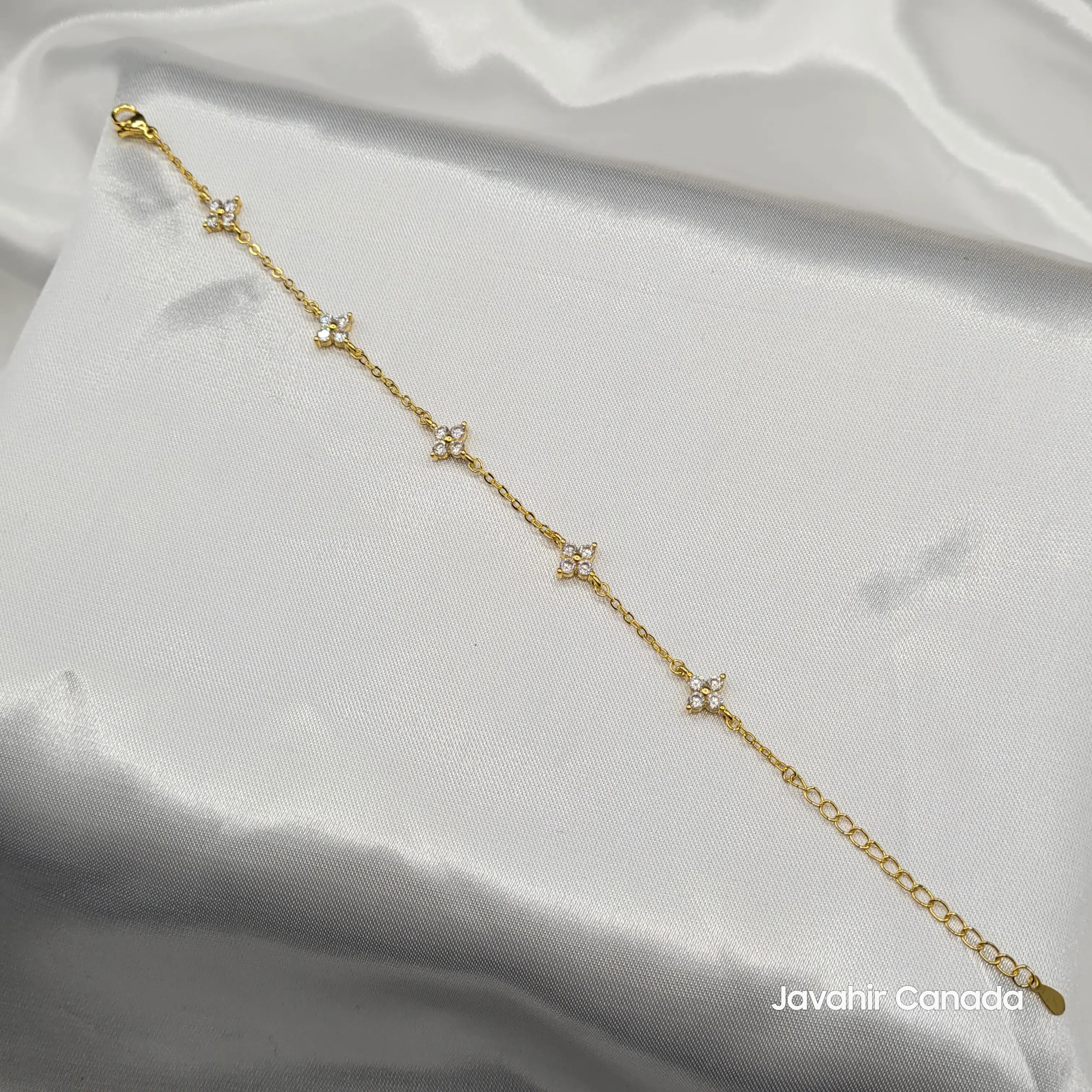 JV4017 gold-plated bracelet with dainty flower-shaped CZ charms displayed on white fabric