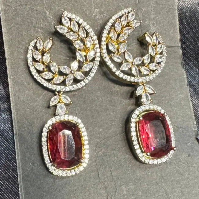 Pair of earrings with hotpink gemstones on a gray card with a dark background
