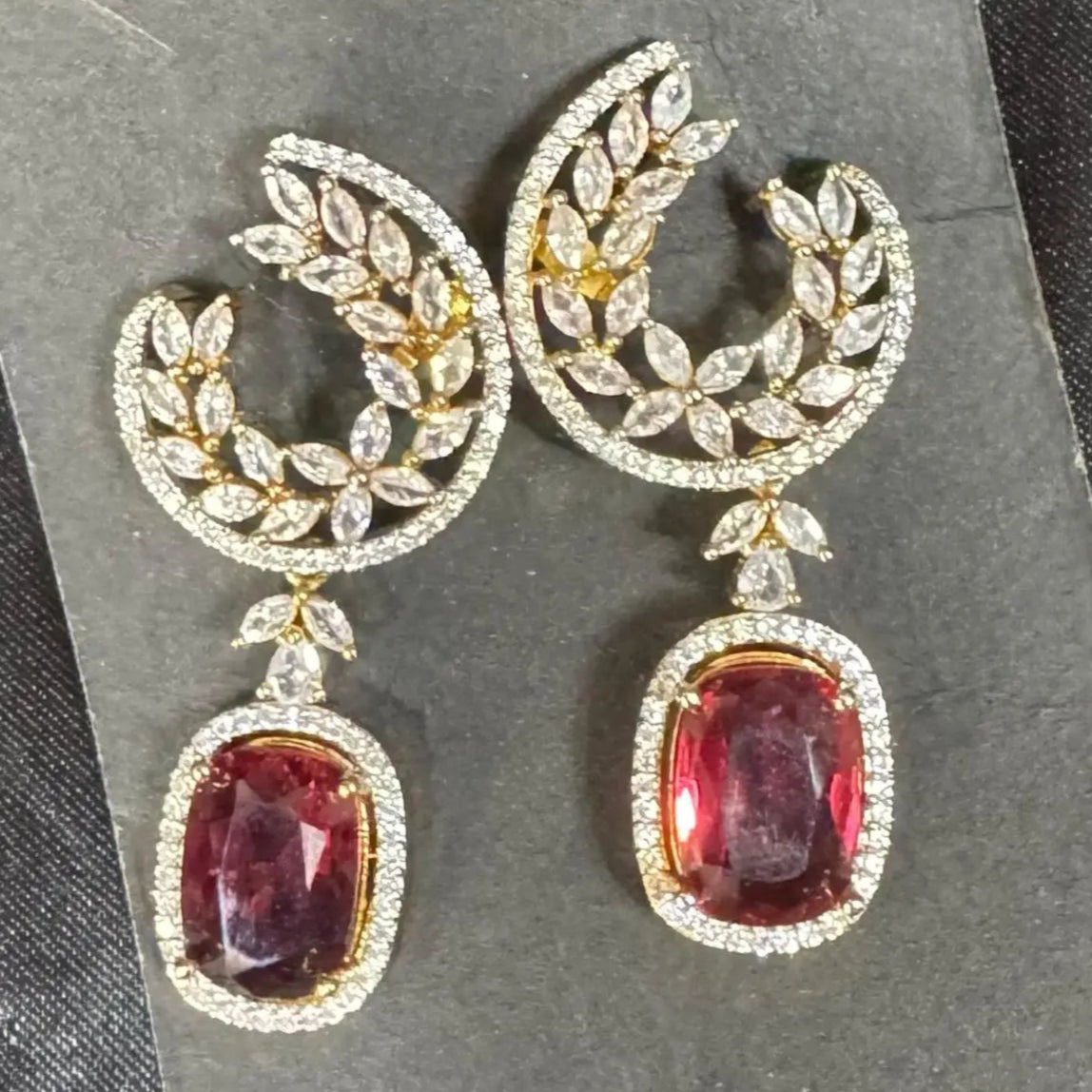 Pair of earrings with hotpink gemstones and gold accents on a gray card.