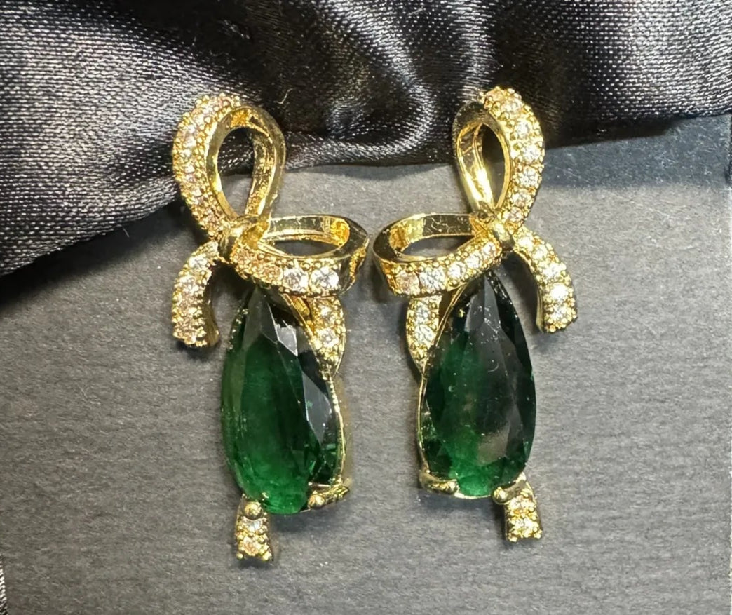 Gold and green gemstone earrings on a black satin background