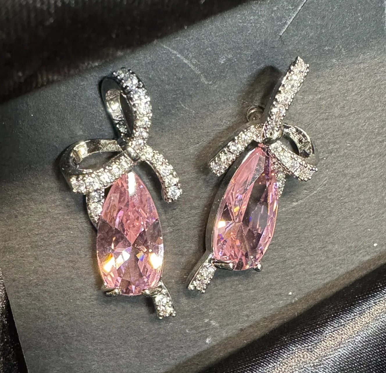 Pair of earrings with pink gemstones on a dark fabric background