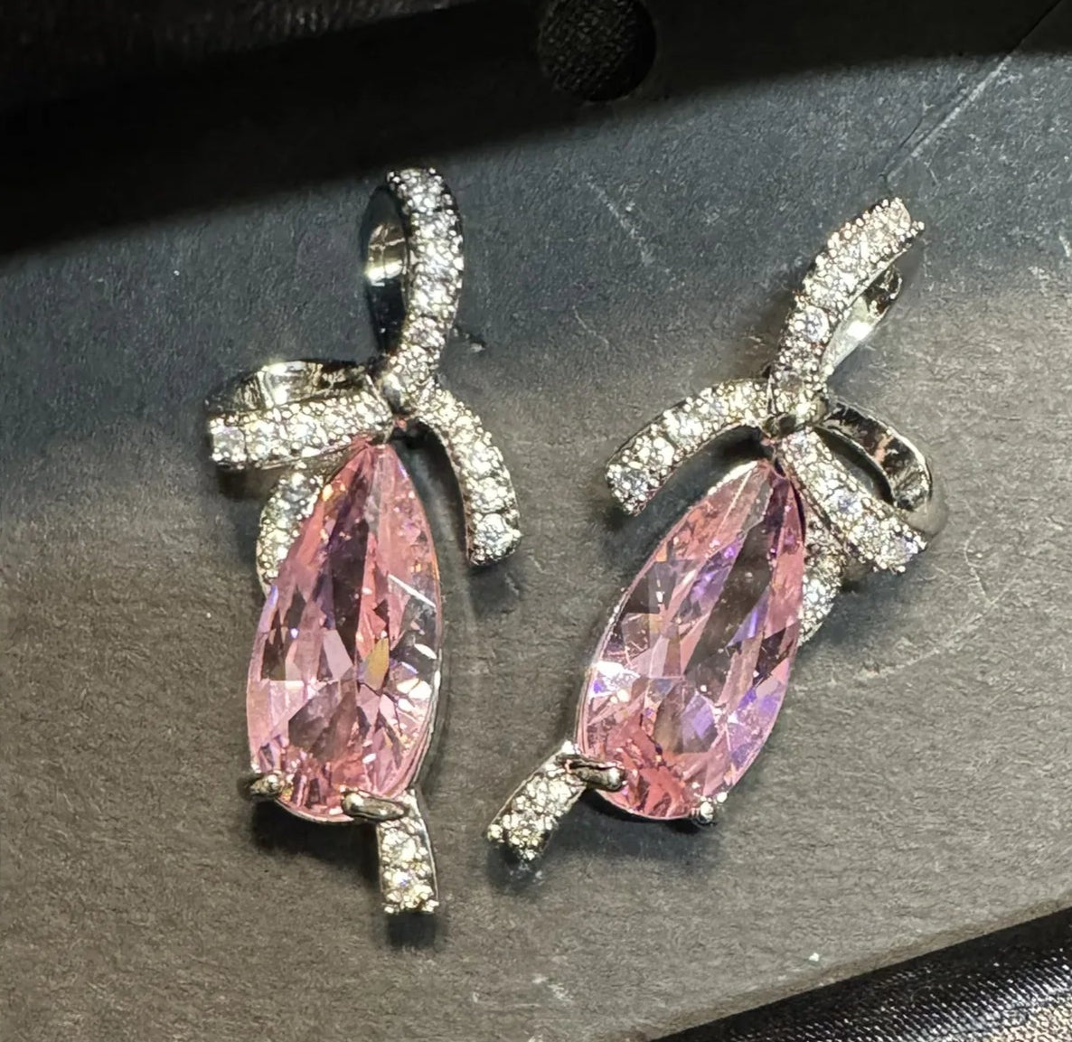 Pink teardrop earrings with silver accents on a gray card.