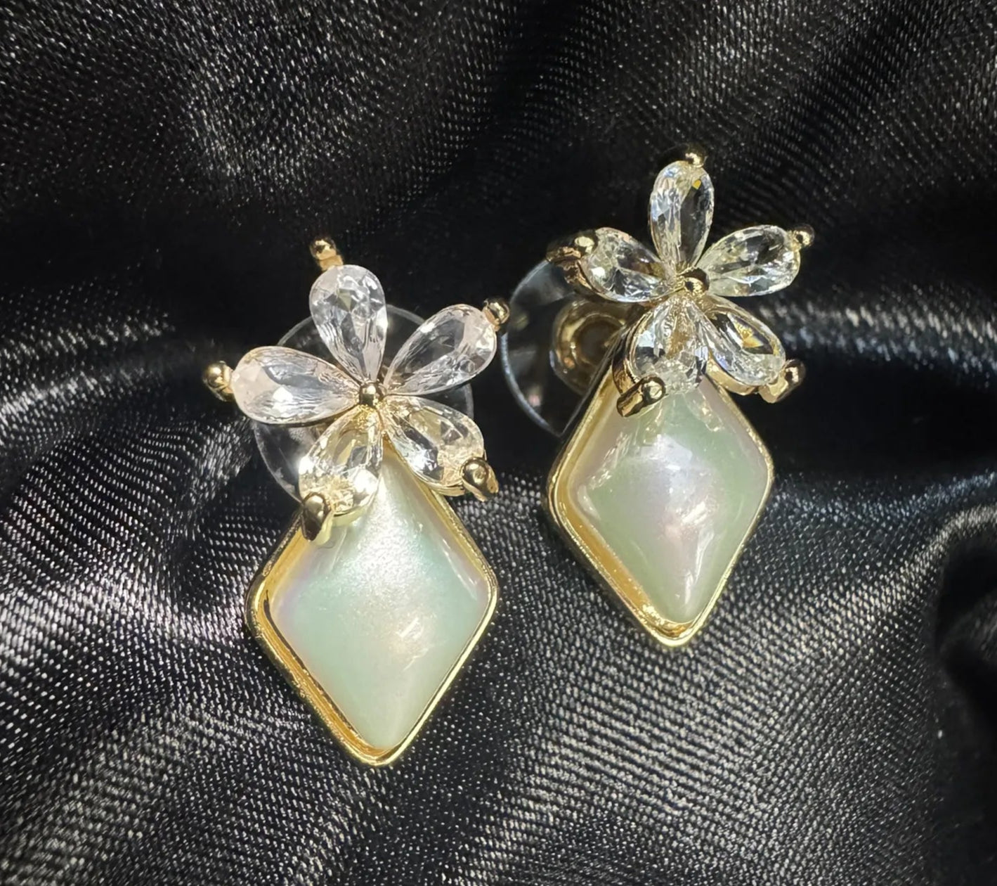 Pair of earrings with floral designs on a black satin background