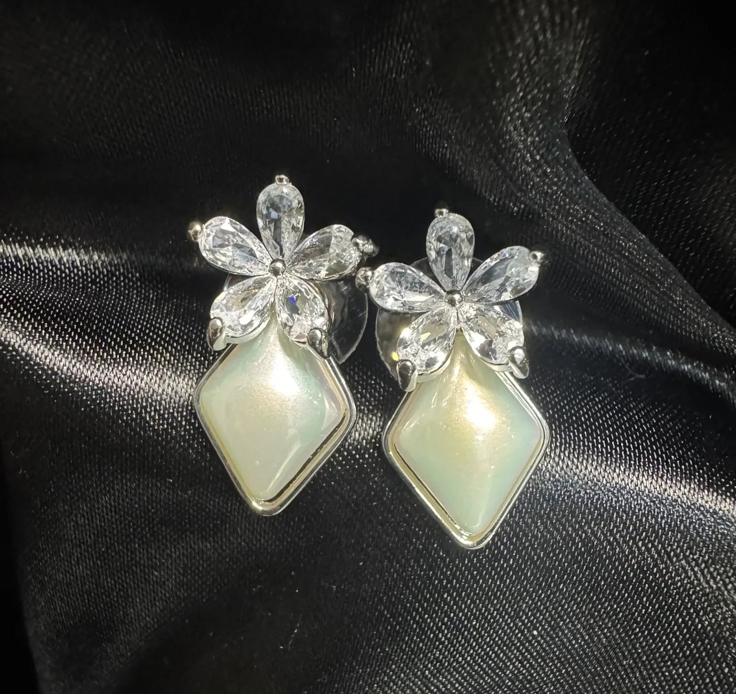 Pair of earrings with butterfly design on a black satin background