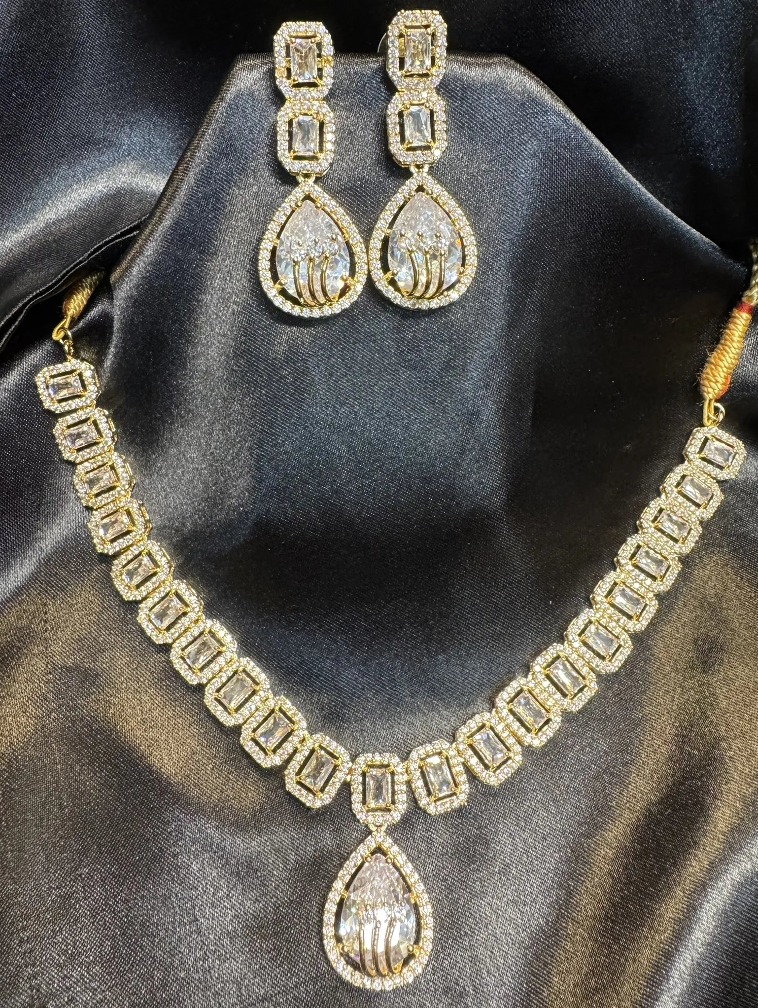 American diamond and gold plated necklace set with clear gemstones on a black satin background