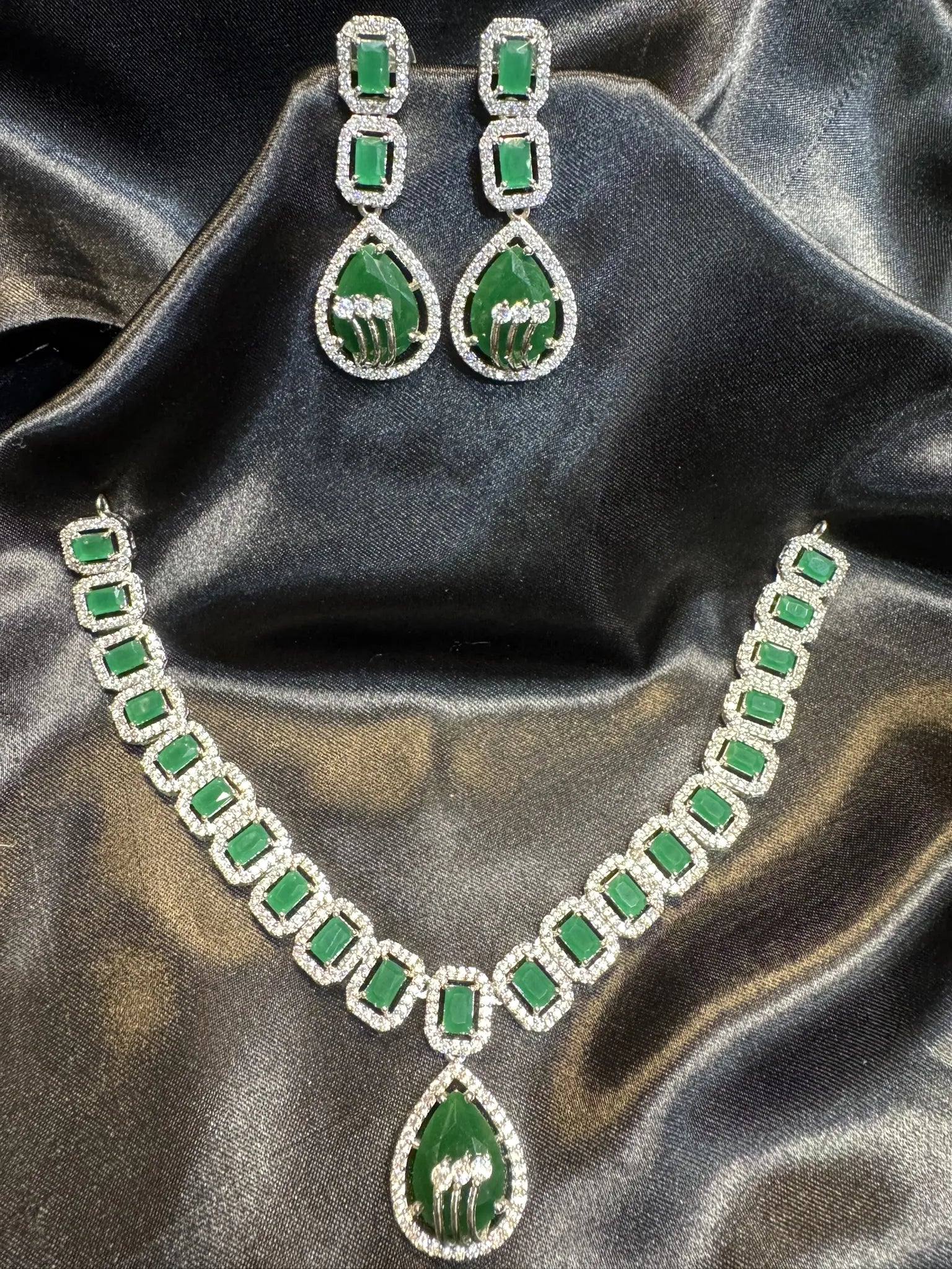 American diamond necklace set with emerald gemstones on a black satin background