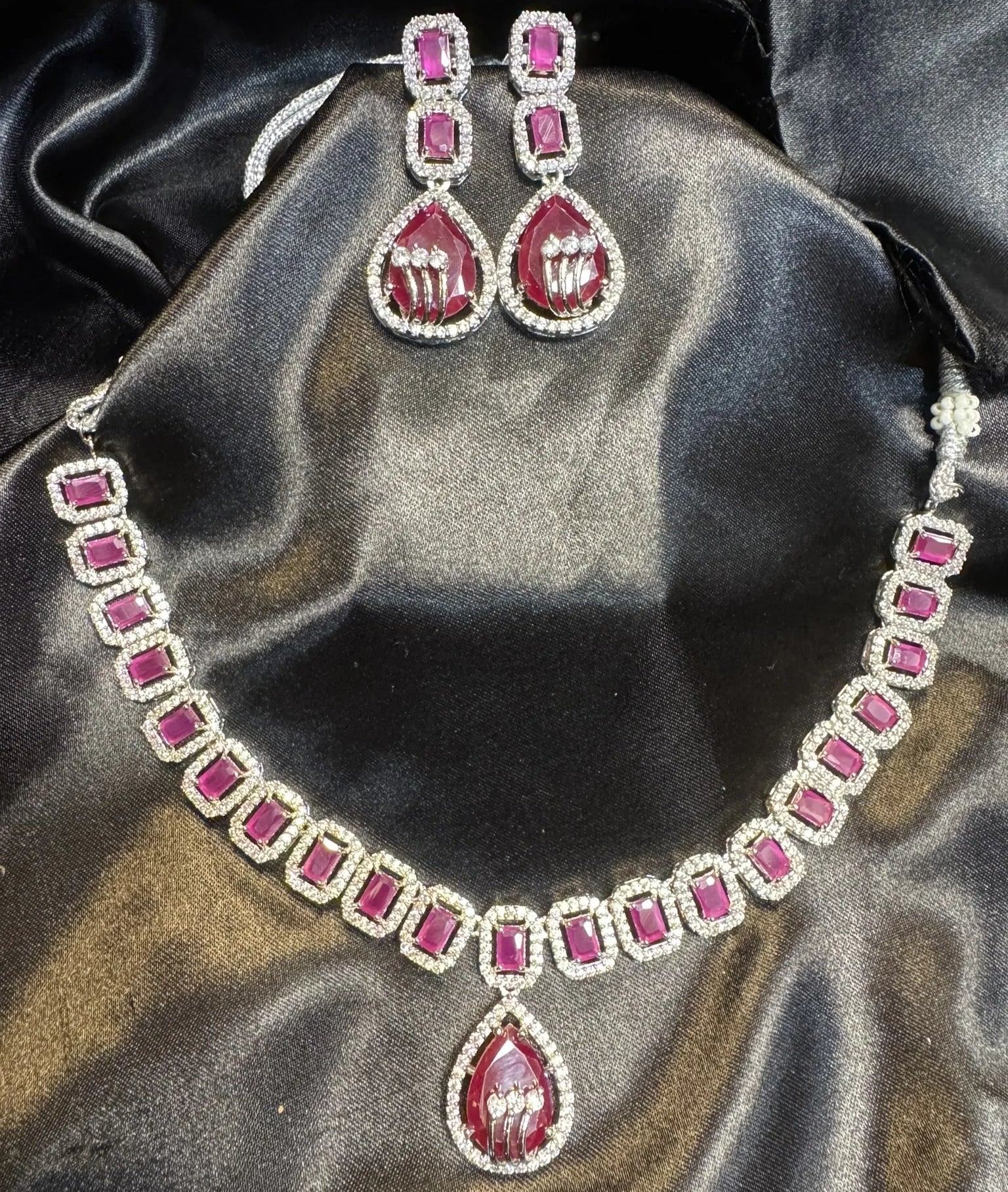 American diamond necklace set with hot pink gemstones on a black satin background