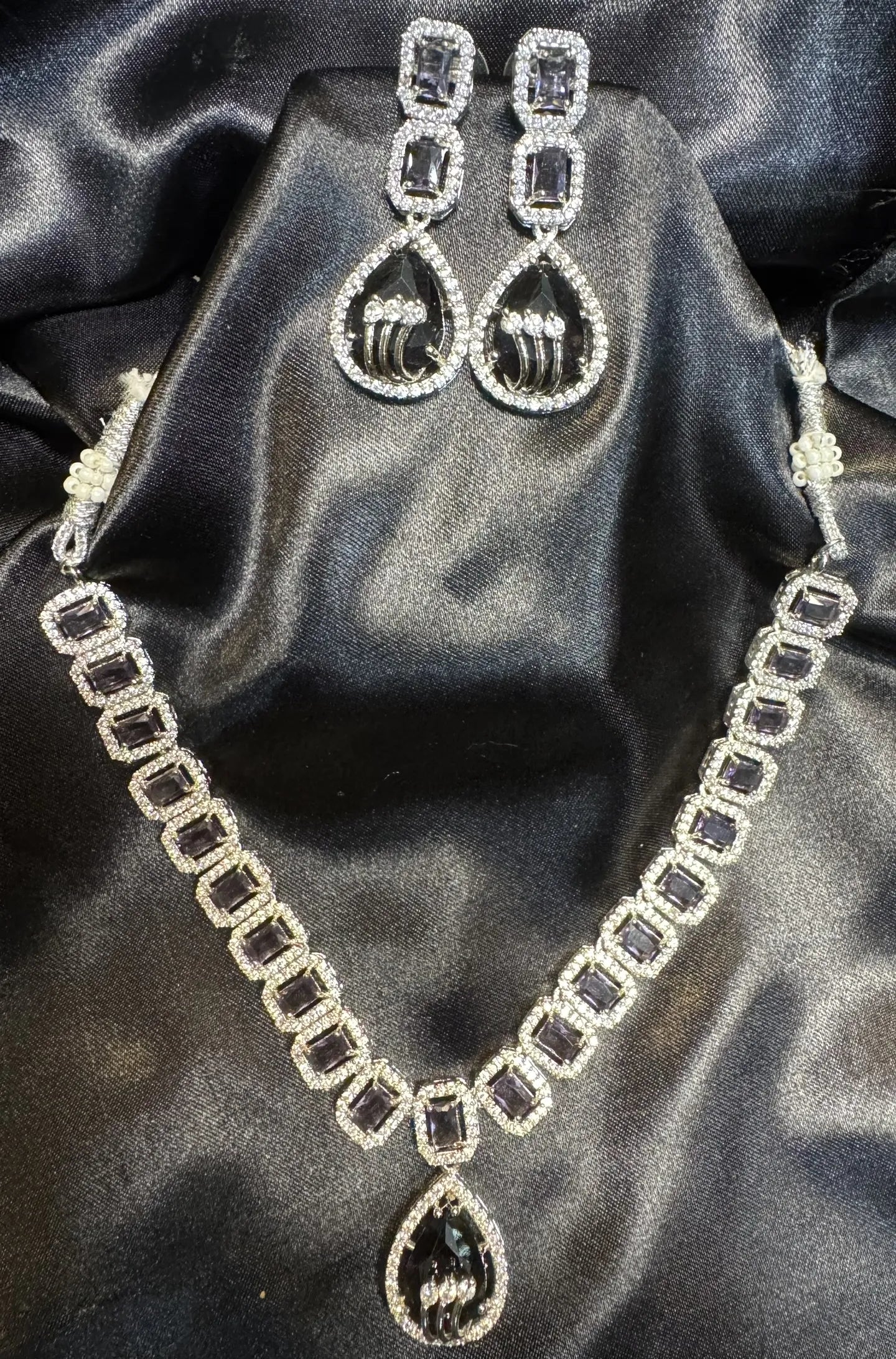 American diamond necklace set with purple gemstones on a black satin background