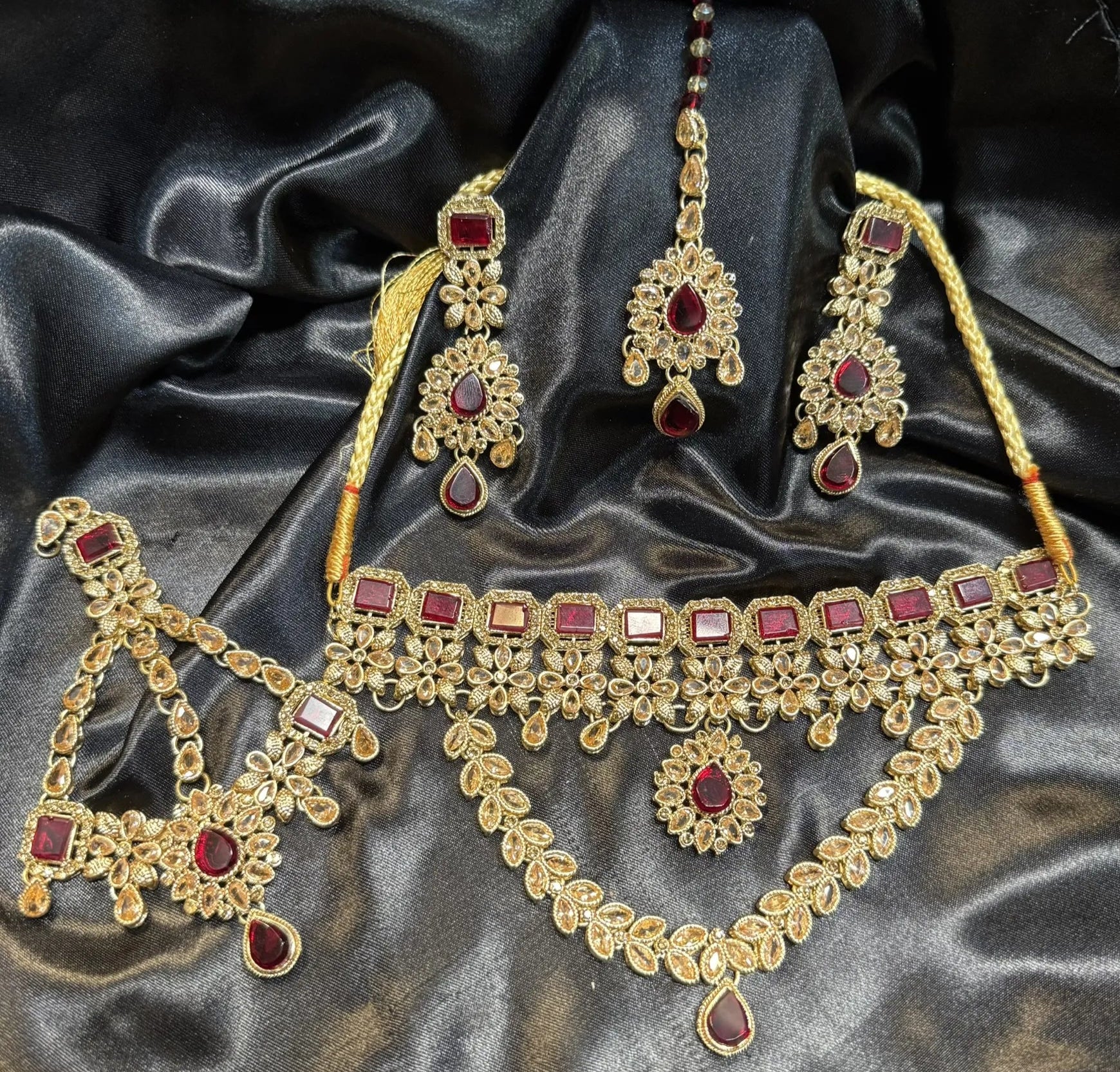 Gold plated necklace with red stones on a dark satin background