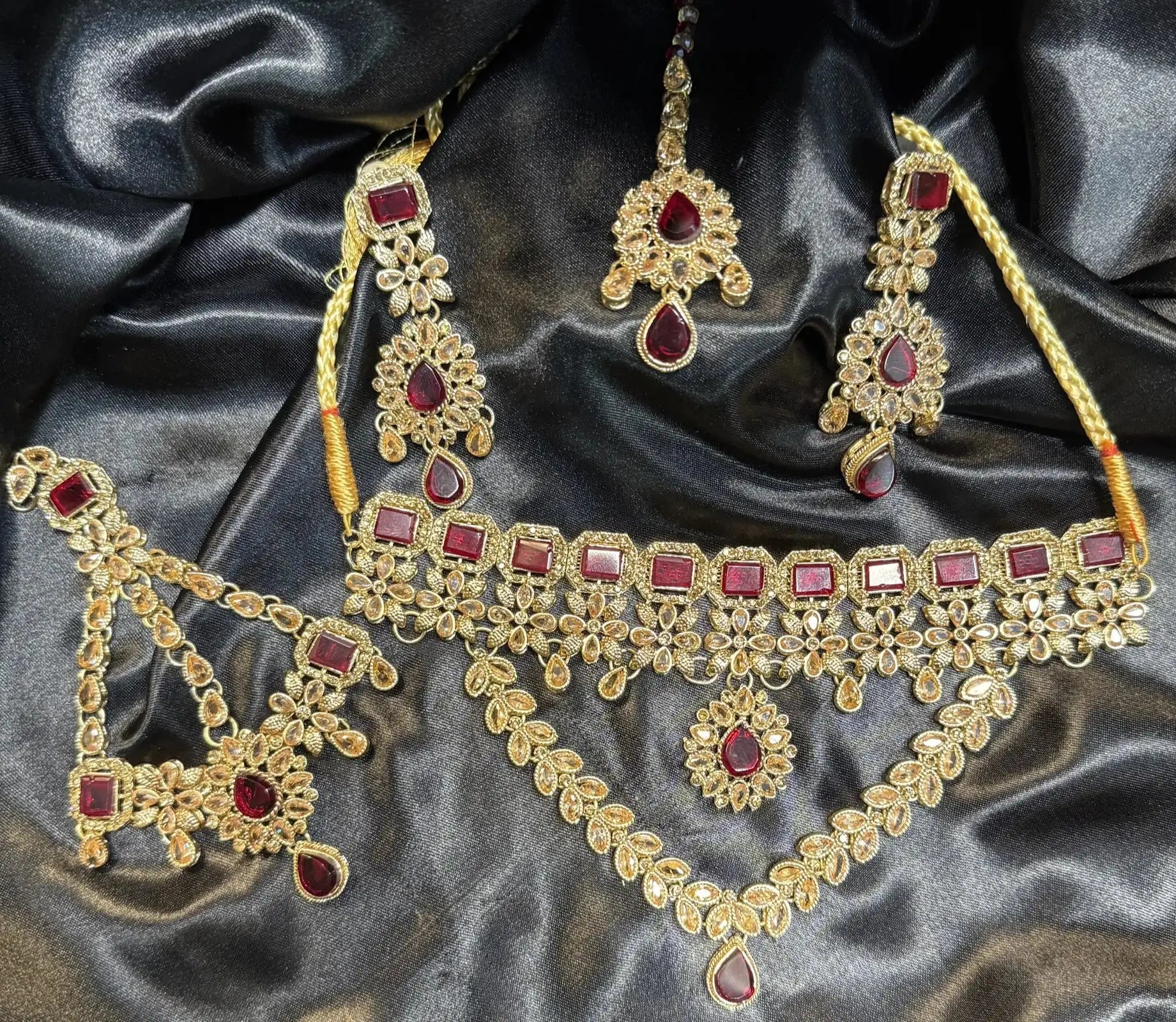 Gold necklace set with red gemstones on a dark satin background