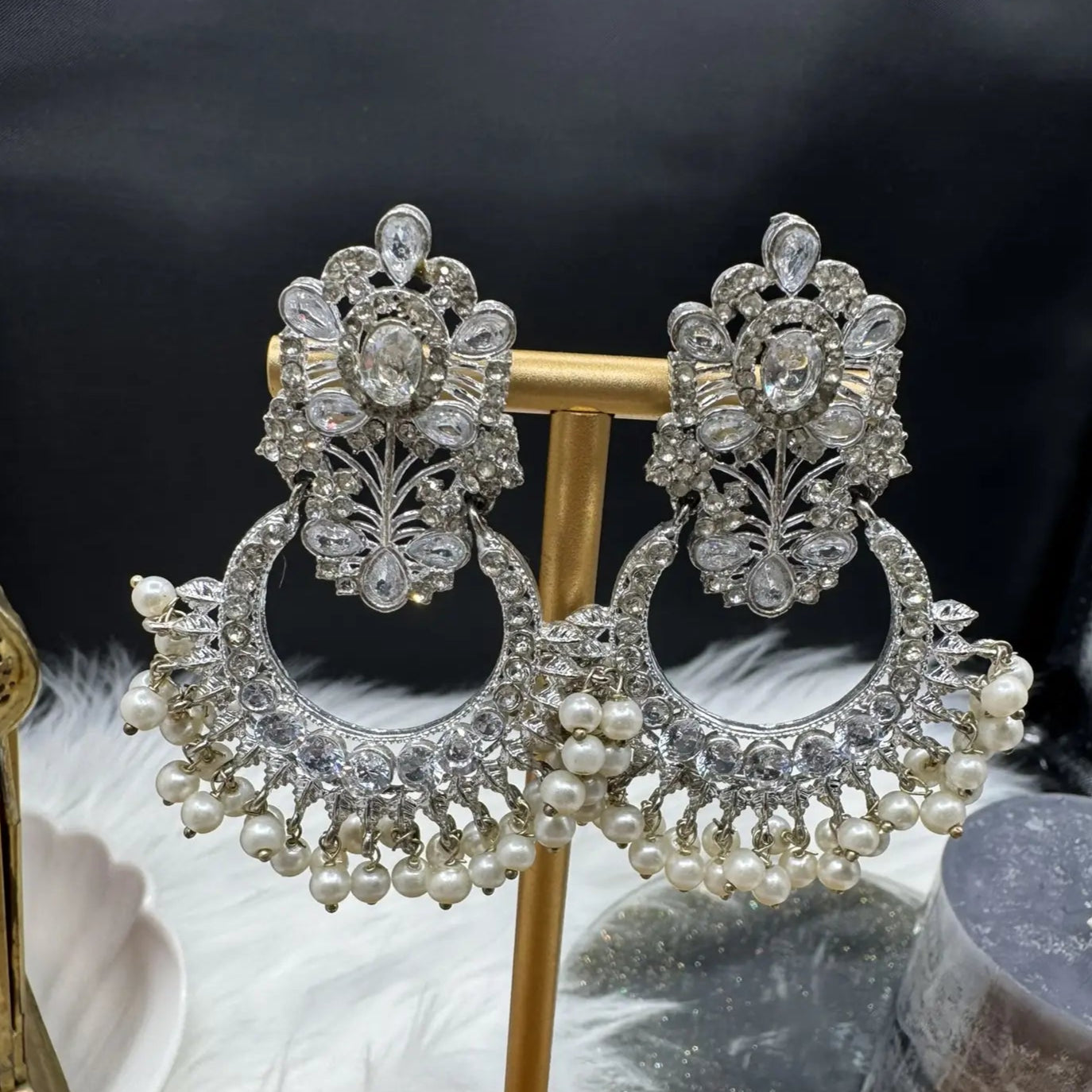 Ornate Pakistani style traditional silver earrings on a stand with a dark background