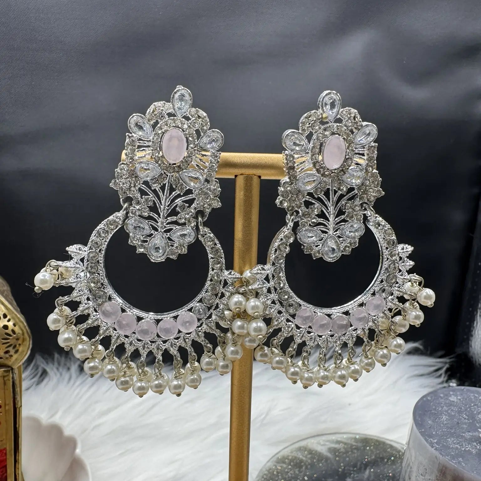 Ornate Pakistani style traditional silver earrings with pink gemstones on a black background