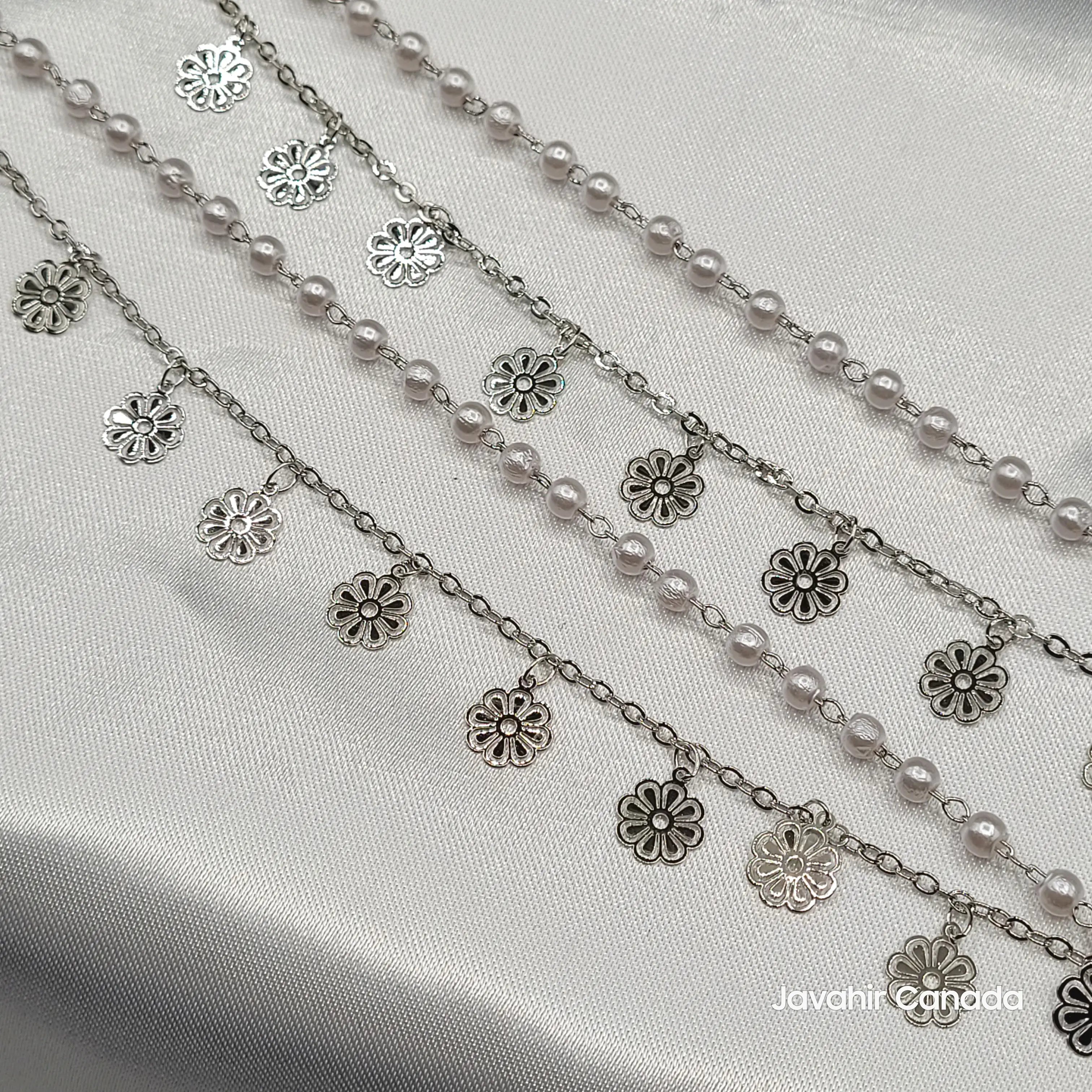 Close-up of silver floral charm anklets with white pearl detailing