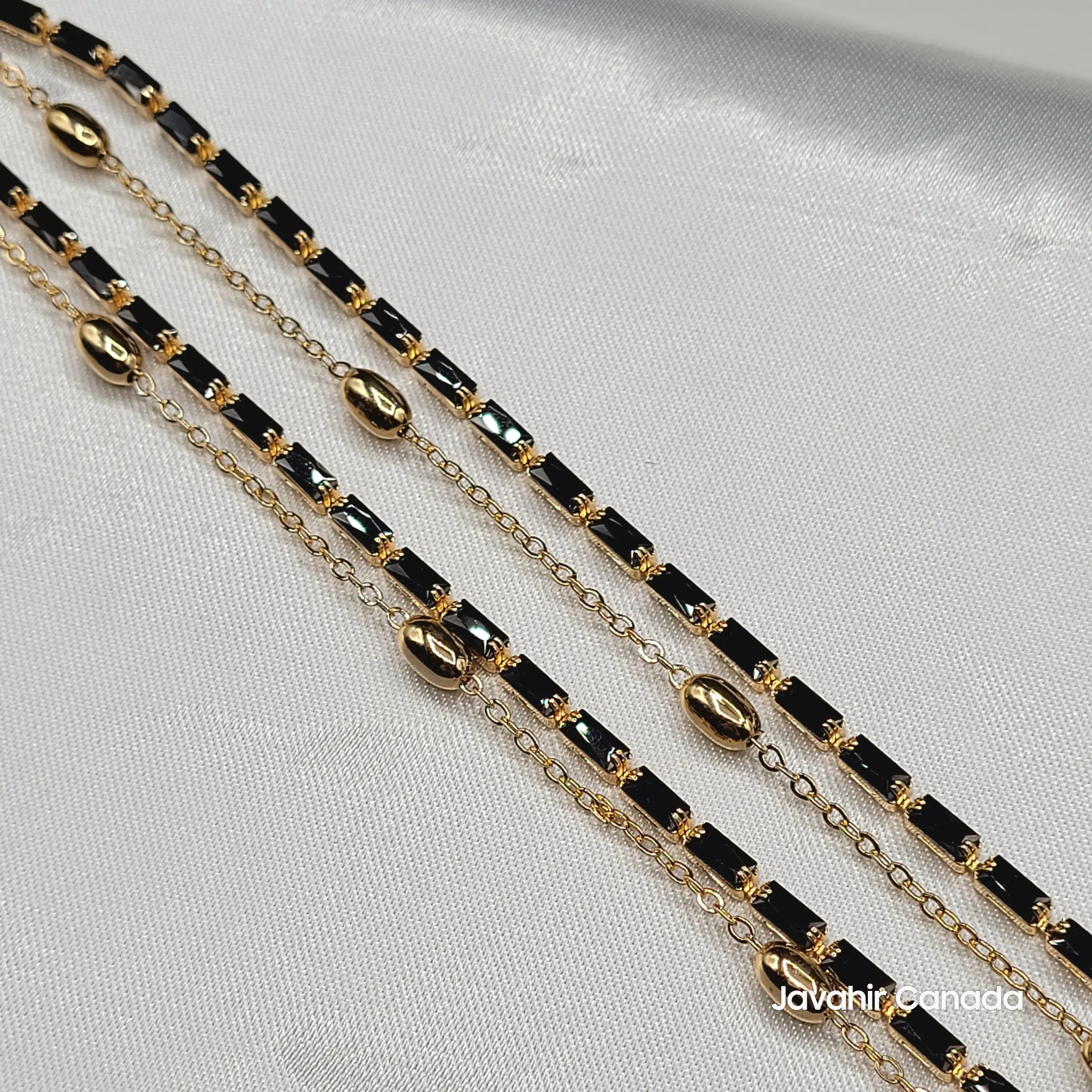Close-up of JV5007 anklets showing sleek black rectangular stones and polished gold bead accents