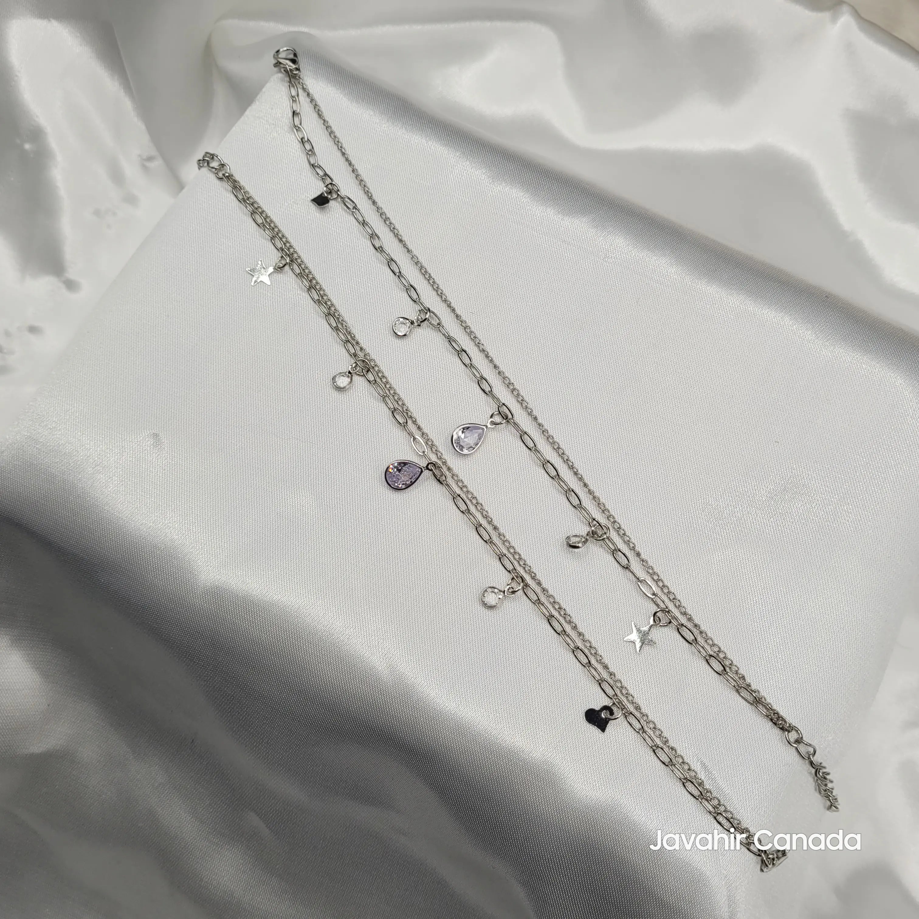JV5012 silver anklet pair featuring heart, star, and teardrop crystal charms on satin display