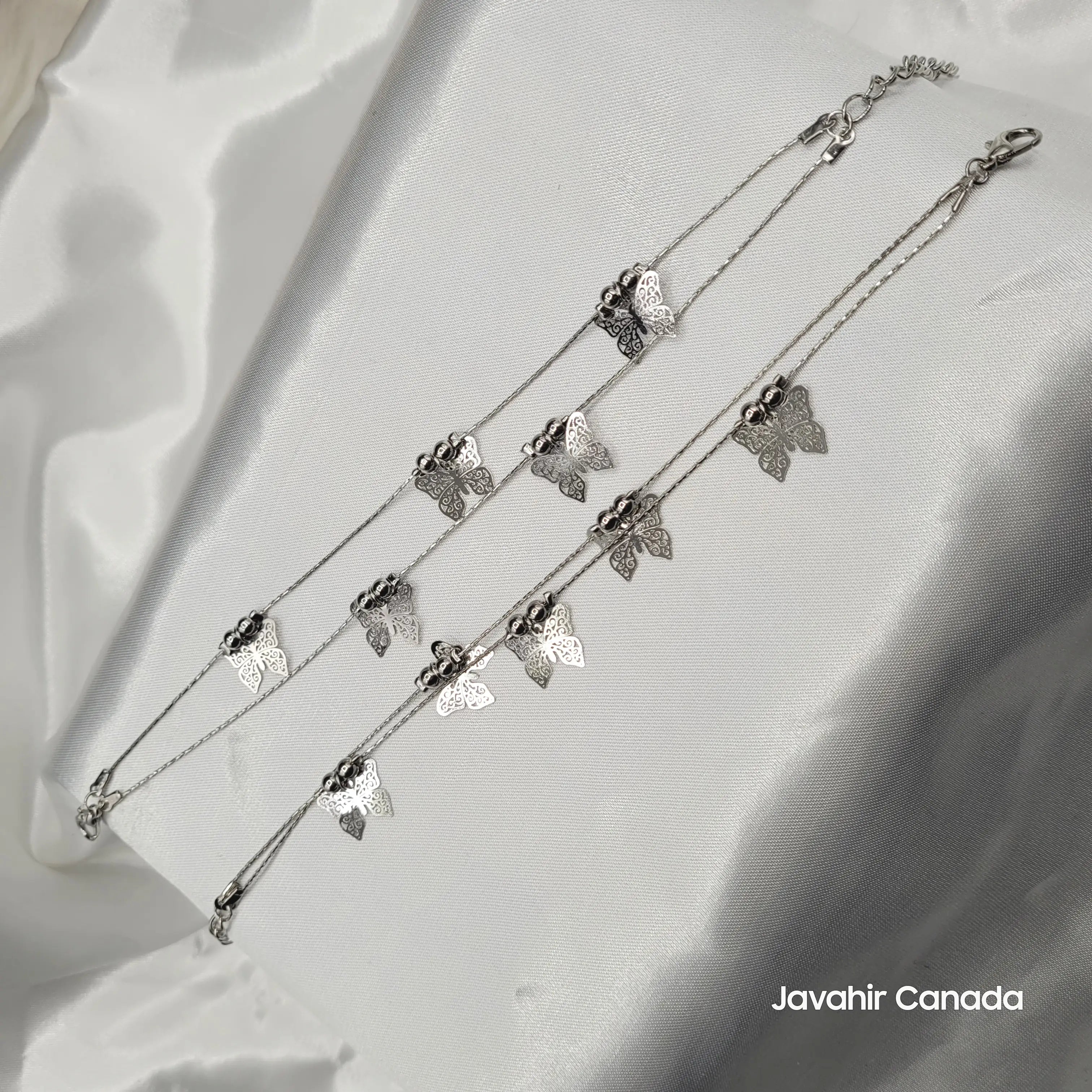 JV5013 silver butterfly anklet pair with detailed charms and beaded accents displayed on white satin