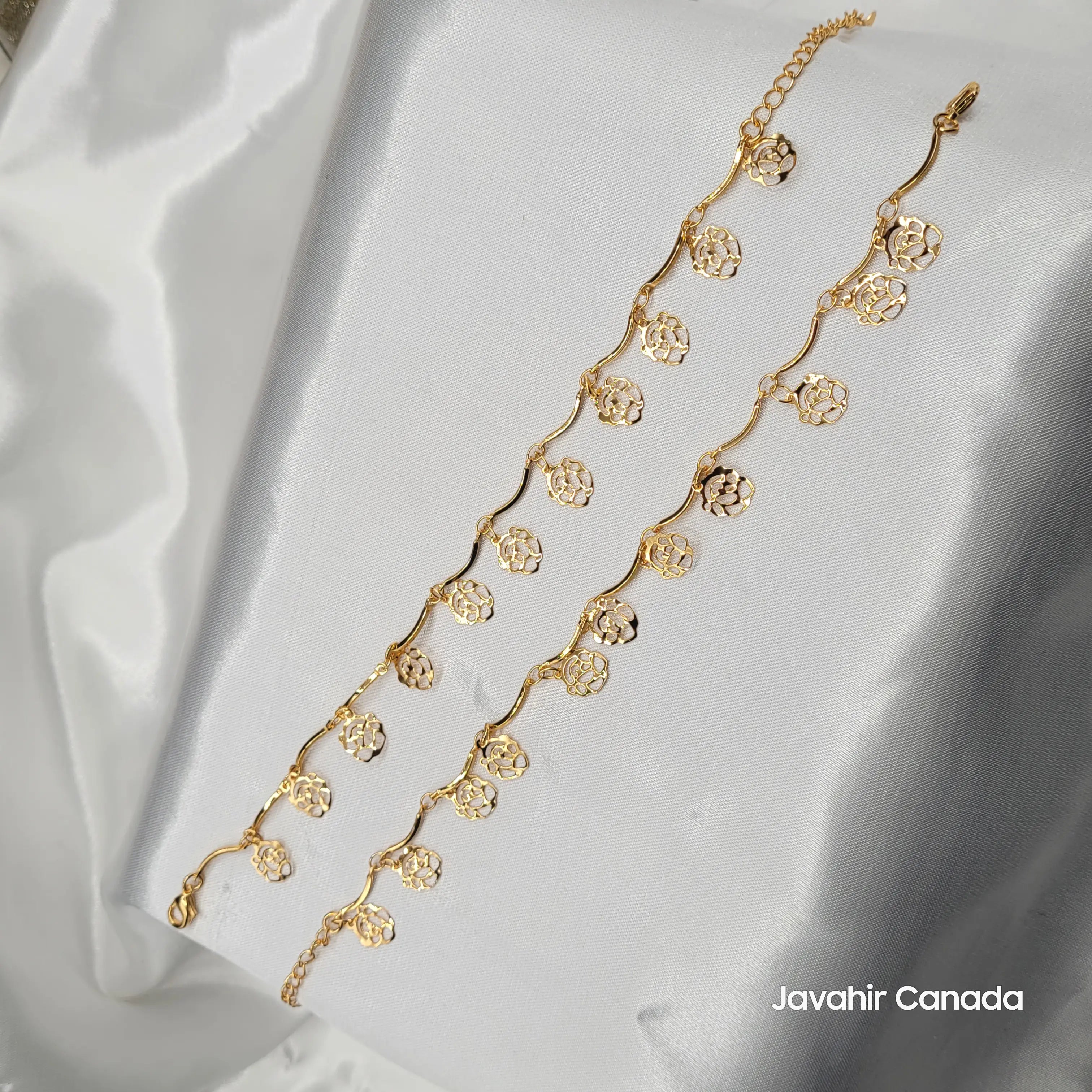 JV5014 gold-plated anklet pair with floral disc charms and wavy chain links displayed on white satin