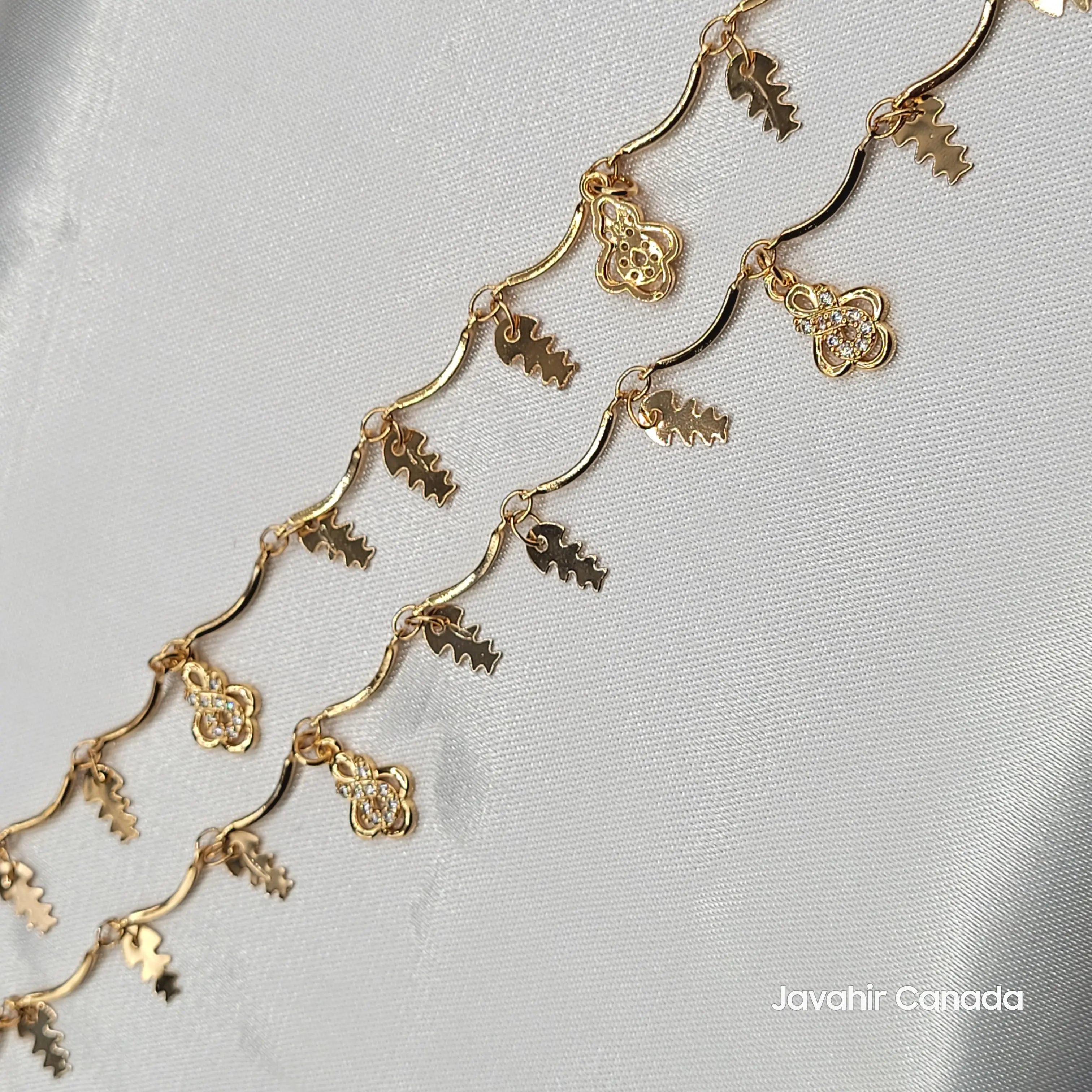 Close-up of JV5015 anklet showing gold floral and leaf charms with delicate wavy chain links