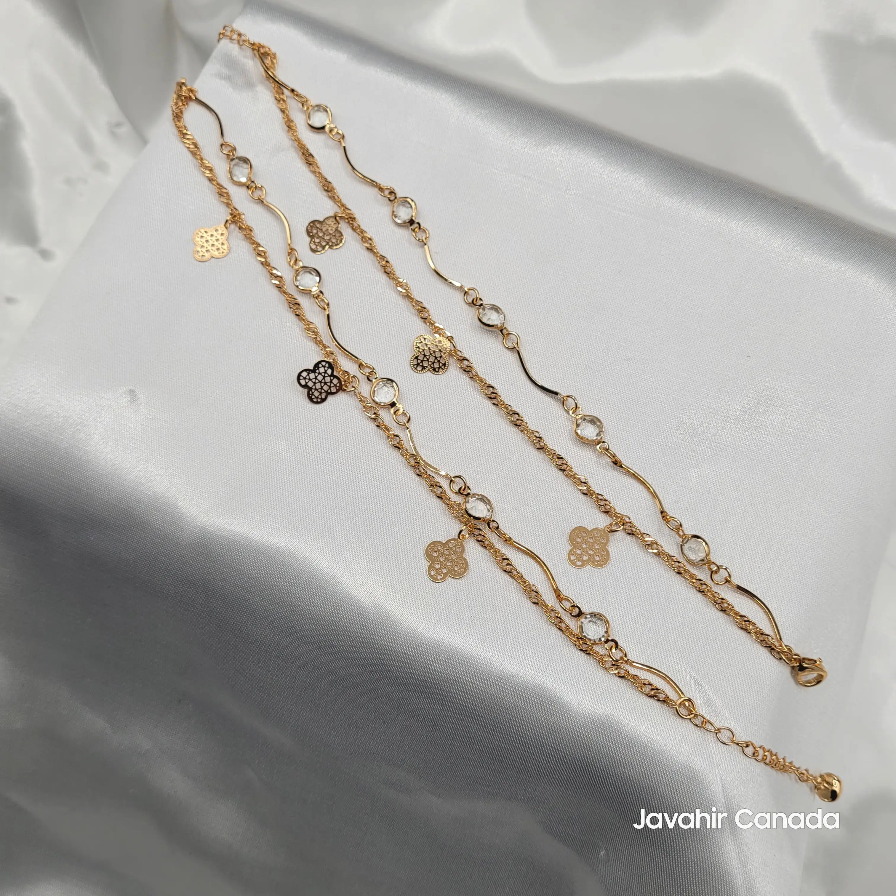 JV5018 gold-plated anklet pair with floral cutout charms and crystal accents on white satin