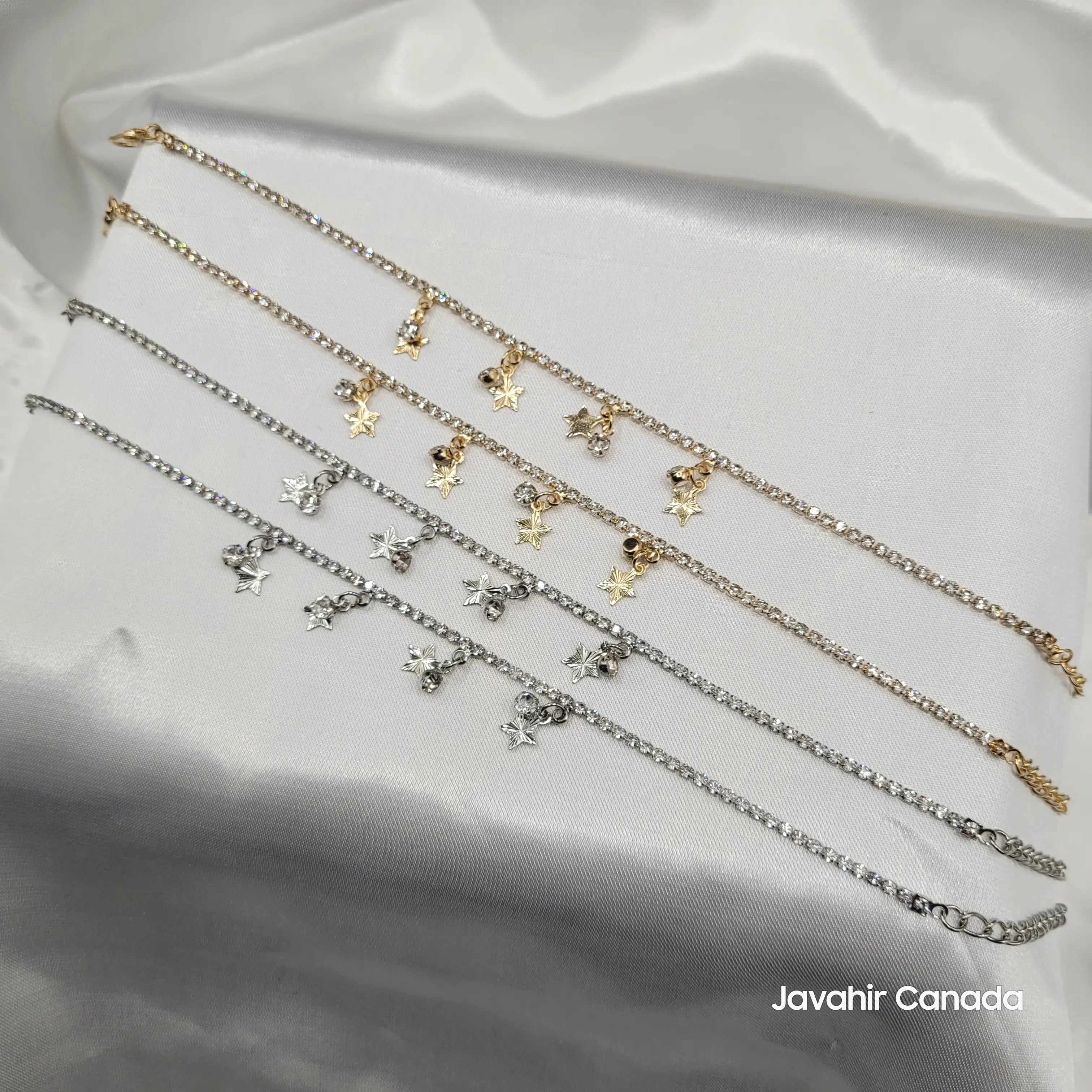 JV5023 anklets in gold and silver with star charms, ghungroos, and American diamonds on white satin background