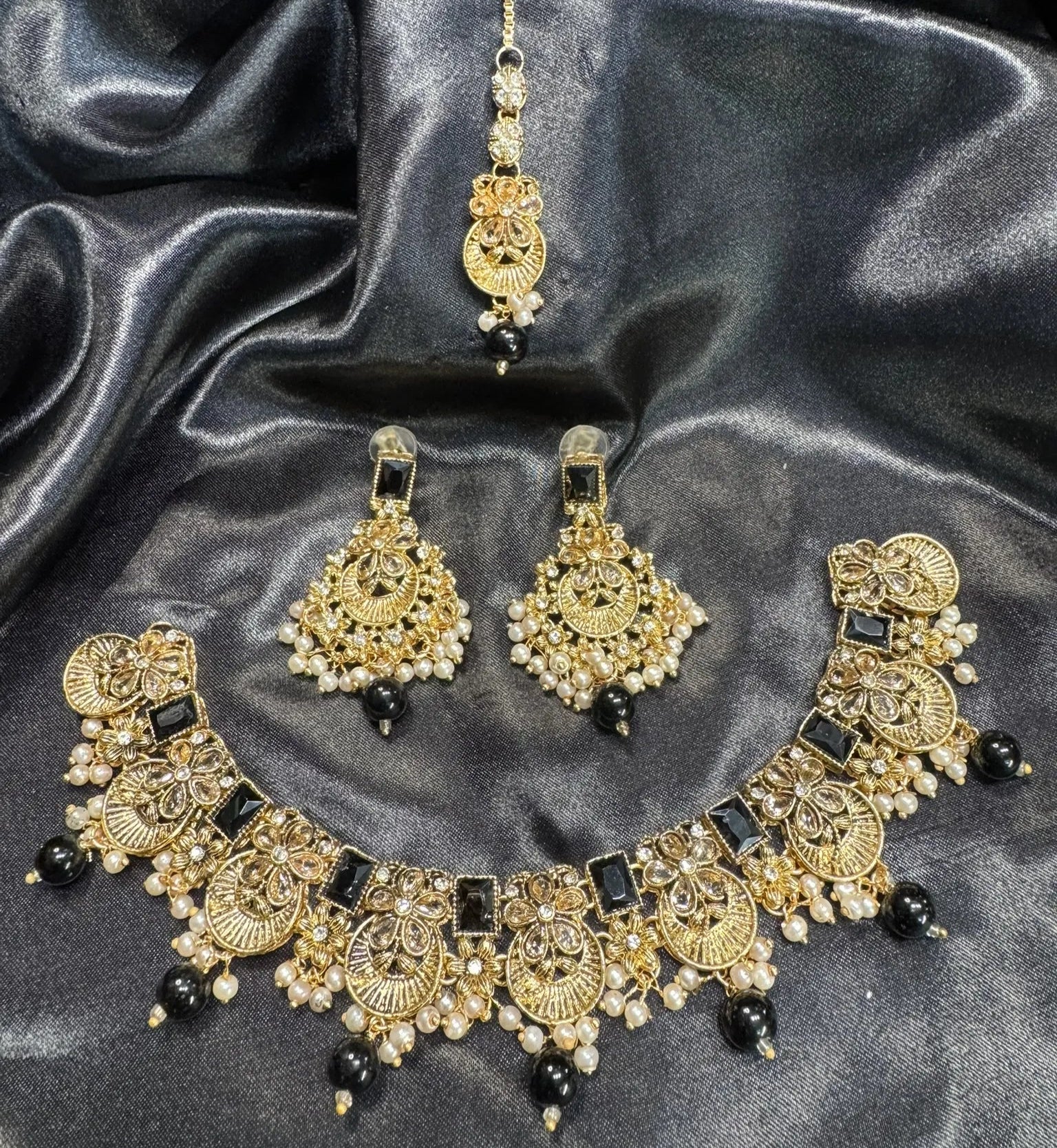 Gold and black jewelry set on a satin surface