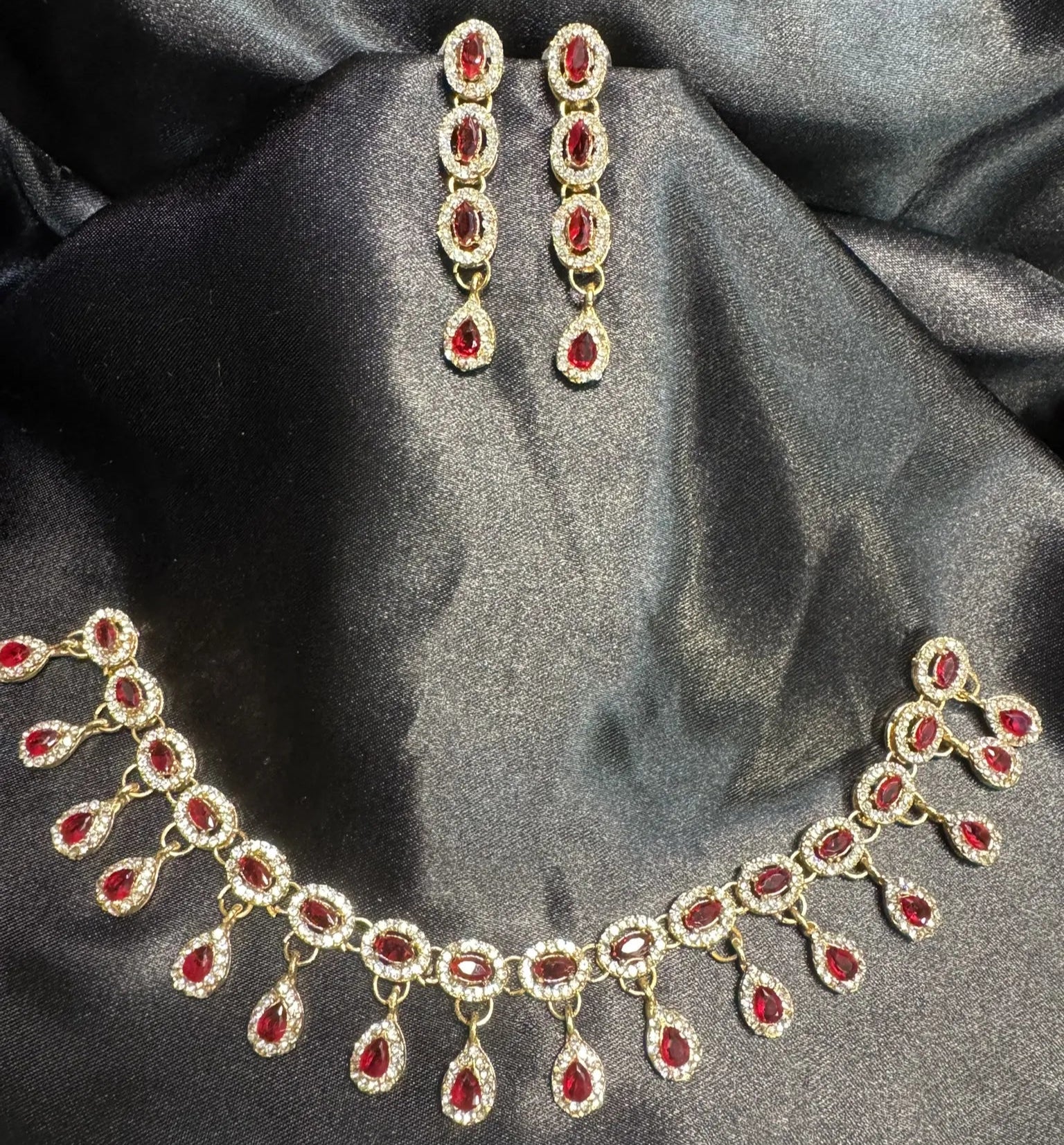 Necklace and earrings with red gemstones on a dark fabric background