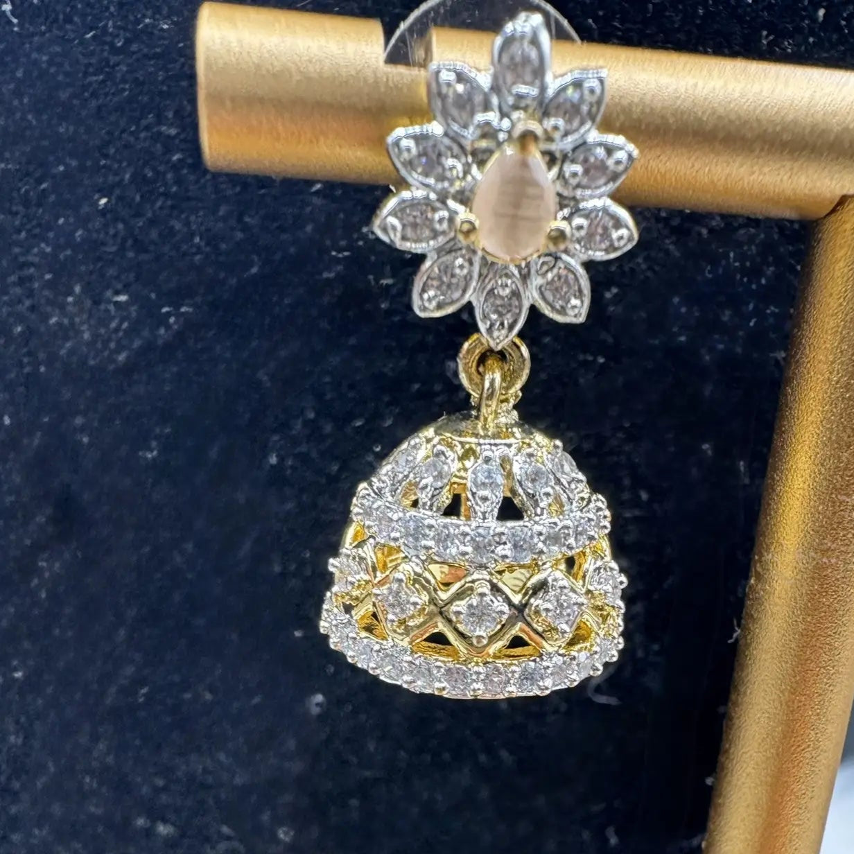 Pakistani style jhumka earring with peach gemstone and a silver base with a blurred background 