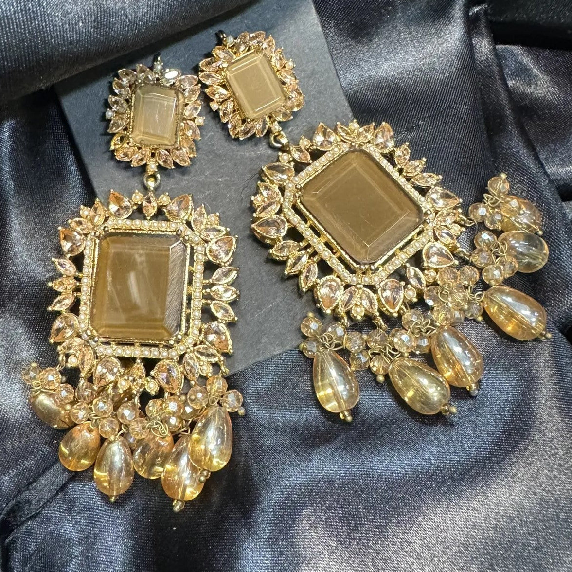 Gold plated earrings with brown stones on a black satin background