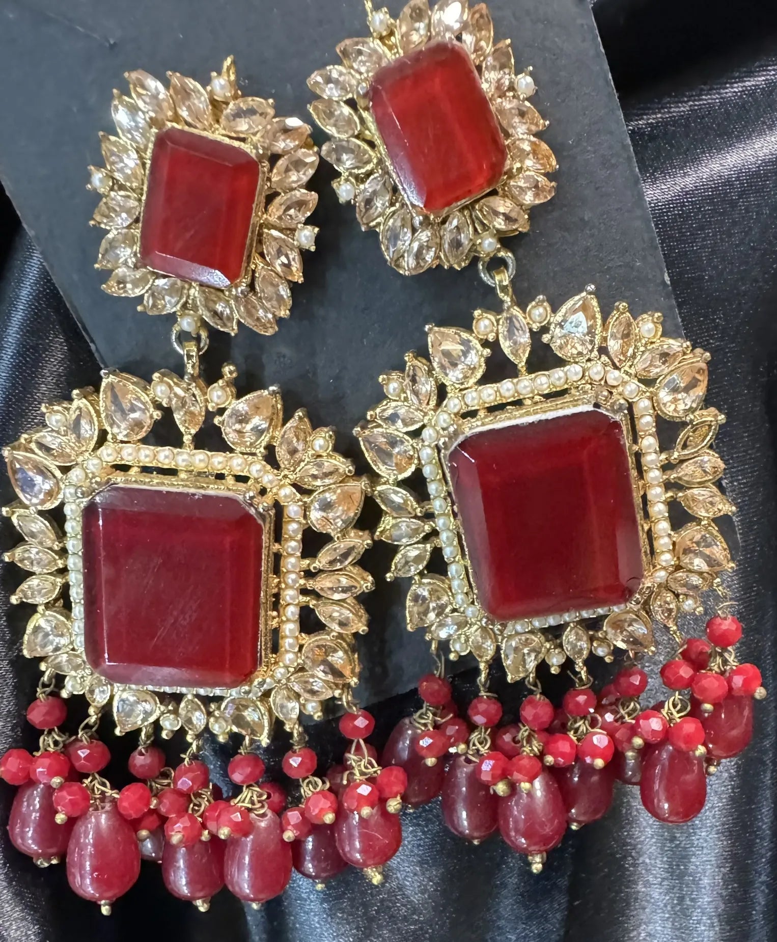 Ornate earrings with red gemstones and gold accents on a black background