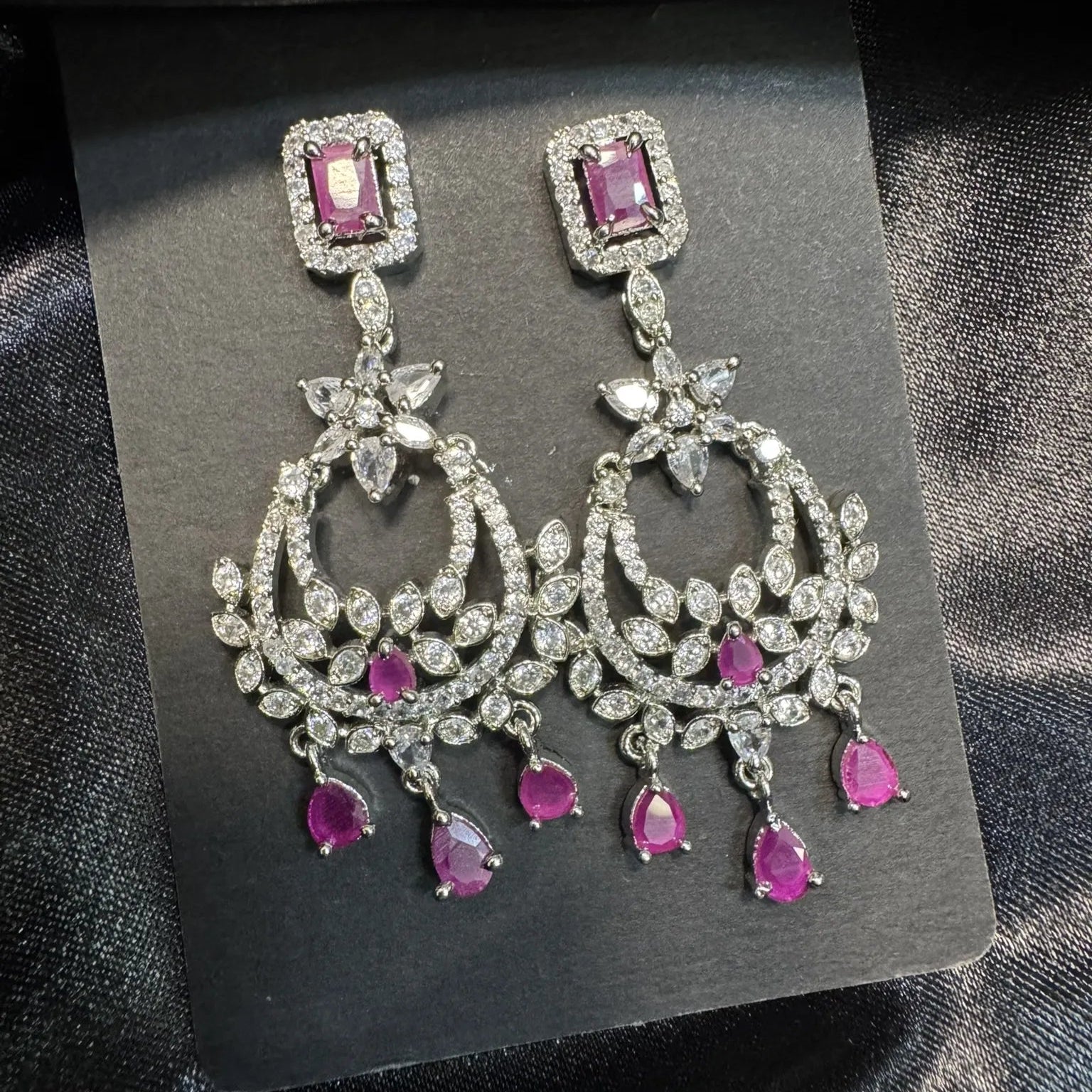 Ornate earrings with hottpink gemstones on a black card