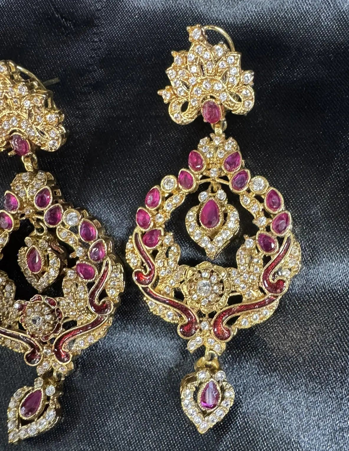 Gold and red gemstone earrings on a dark fabric background