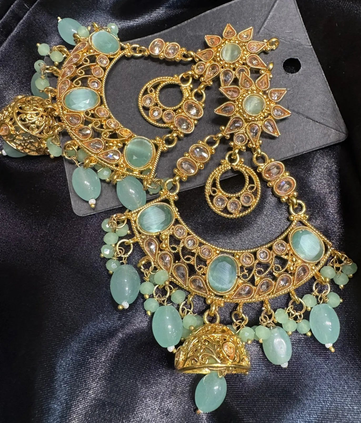 Ornate gold and teal gemstone necklace on a black satin background