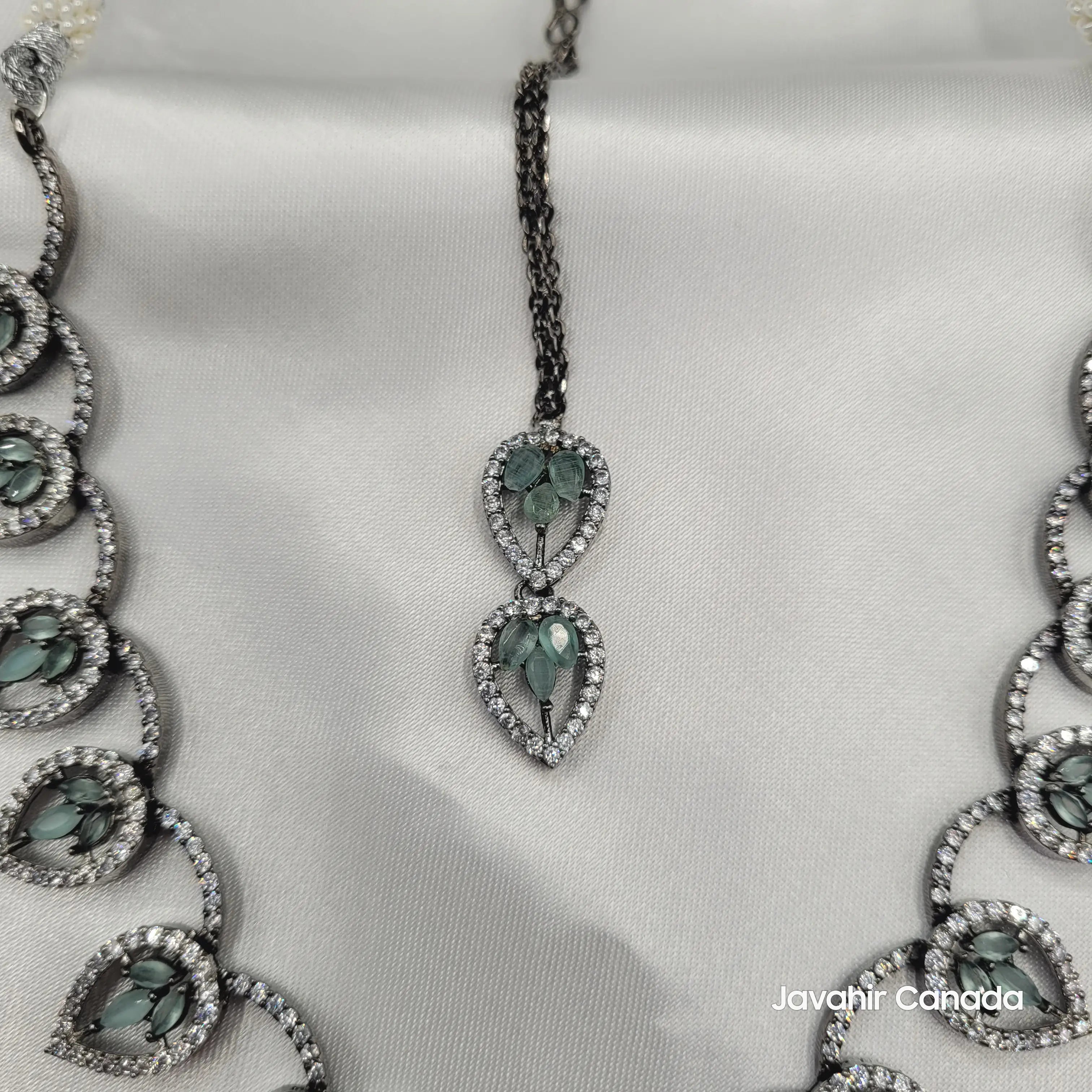 Close-up of the tika pendant featuring double teardrop design with CZ and mint leaf stones