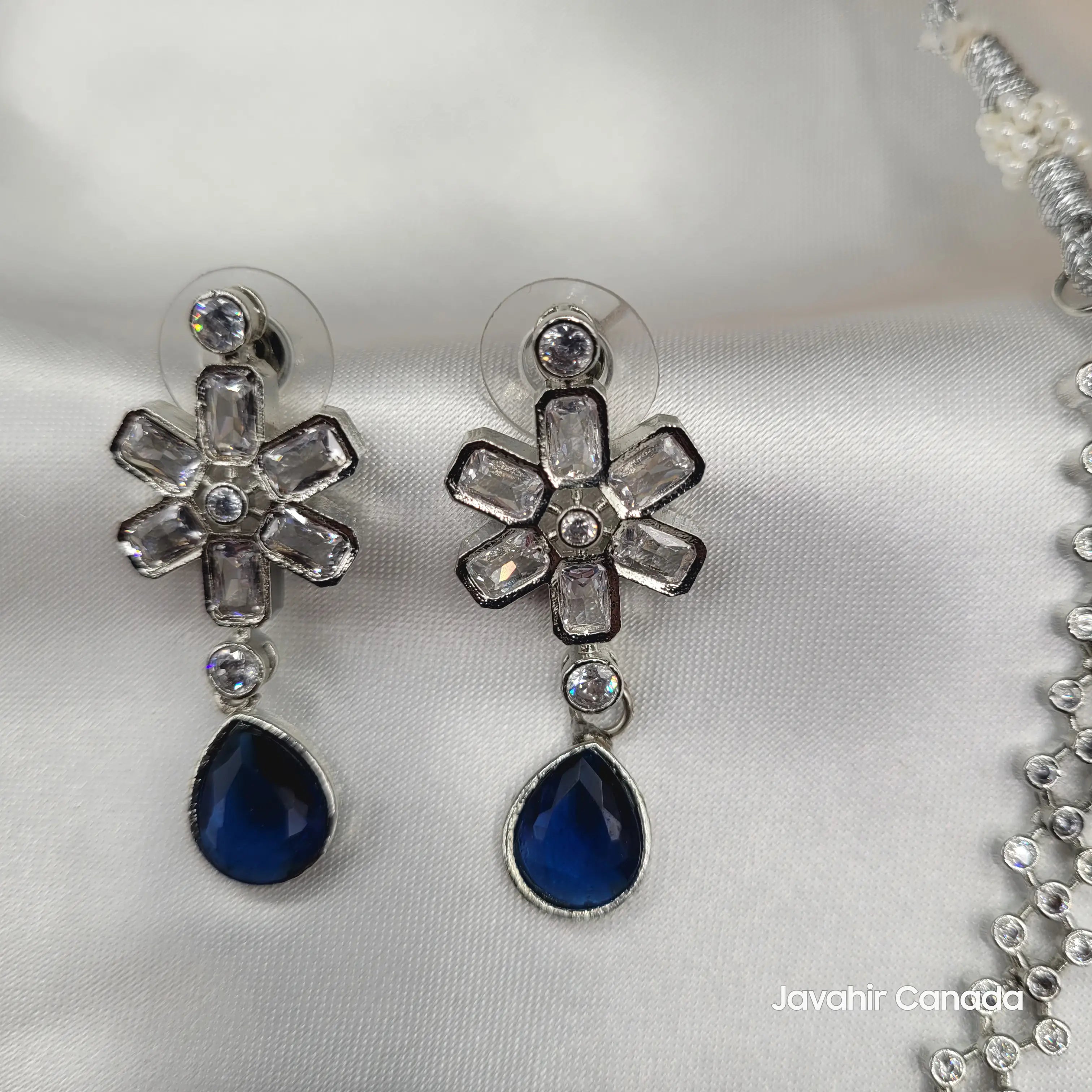 Close-up of sapphire blue teardrop earrings with floral CZ top
