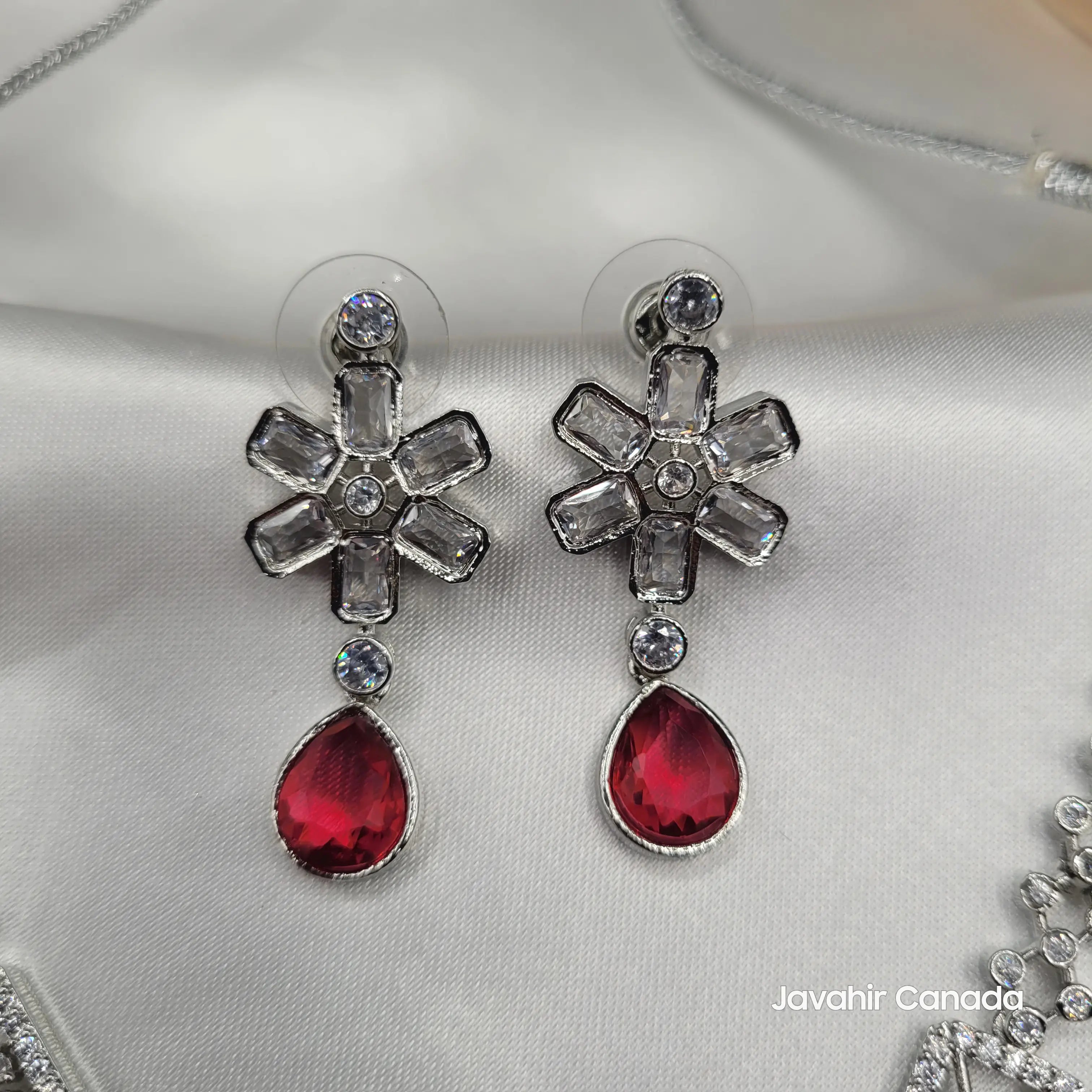 Close-up of JV14 earrings with ruby red teardrop and floral CZ design