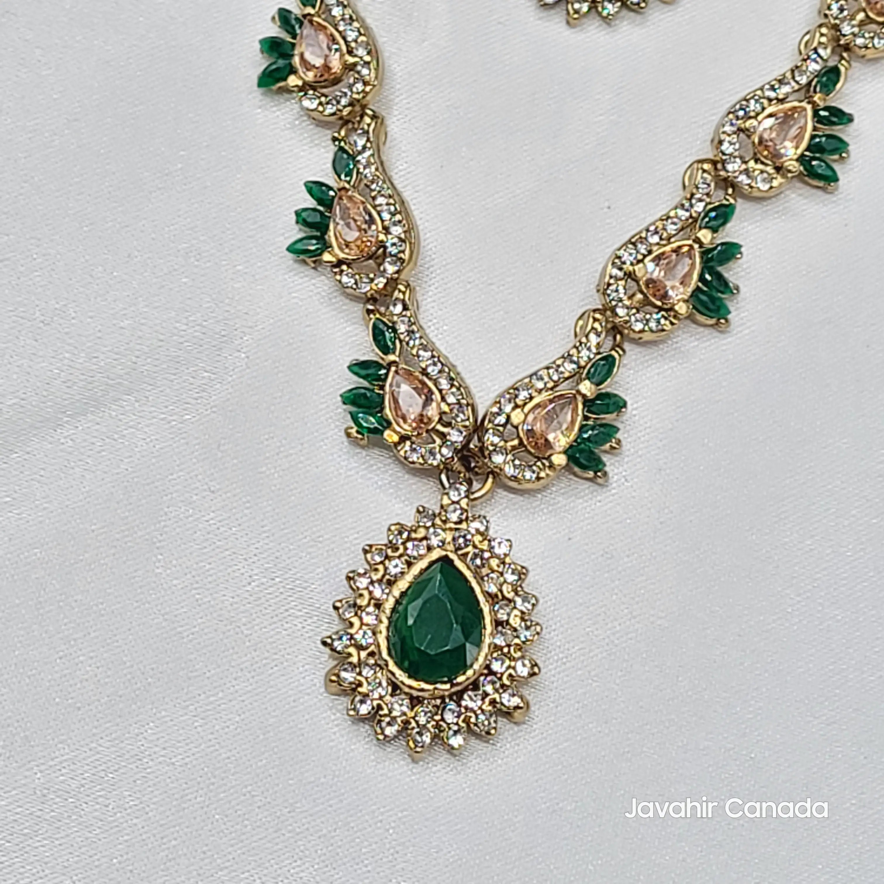 Close-up of JV142 emerald green pendant surrounded by gold and green floral elements