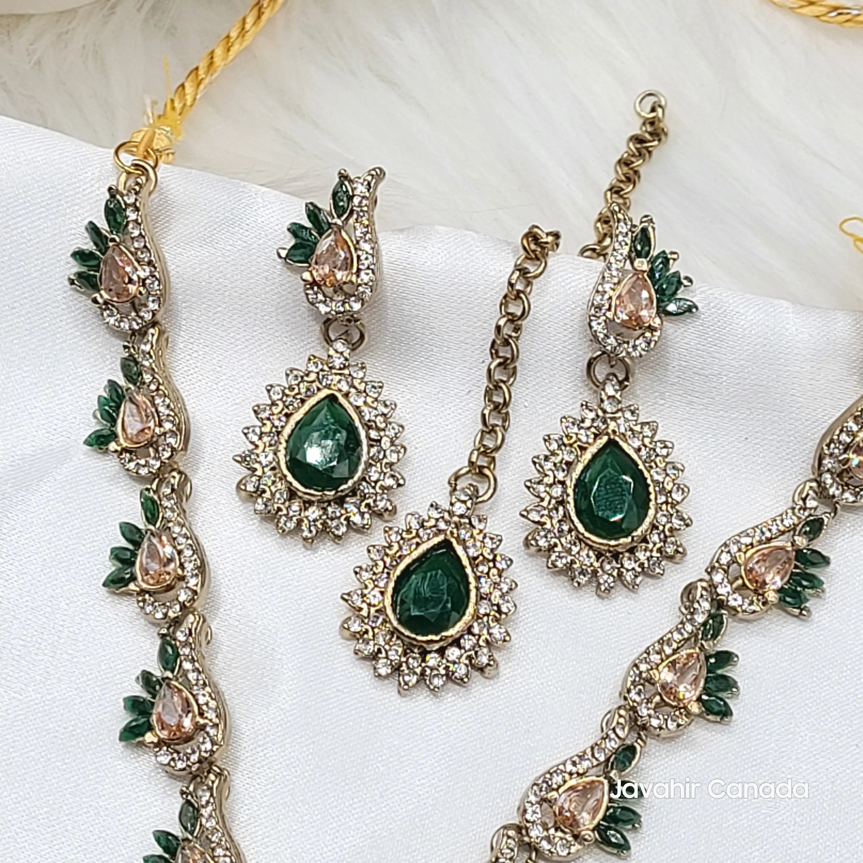 Jewelry set with green gemstones and gold accents on a white background