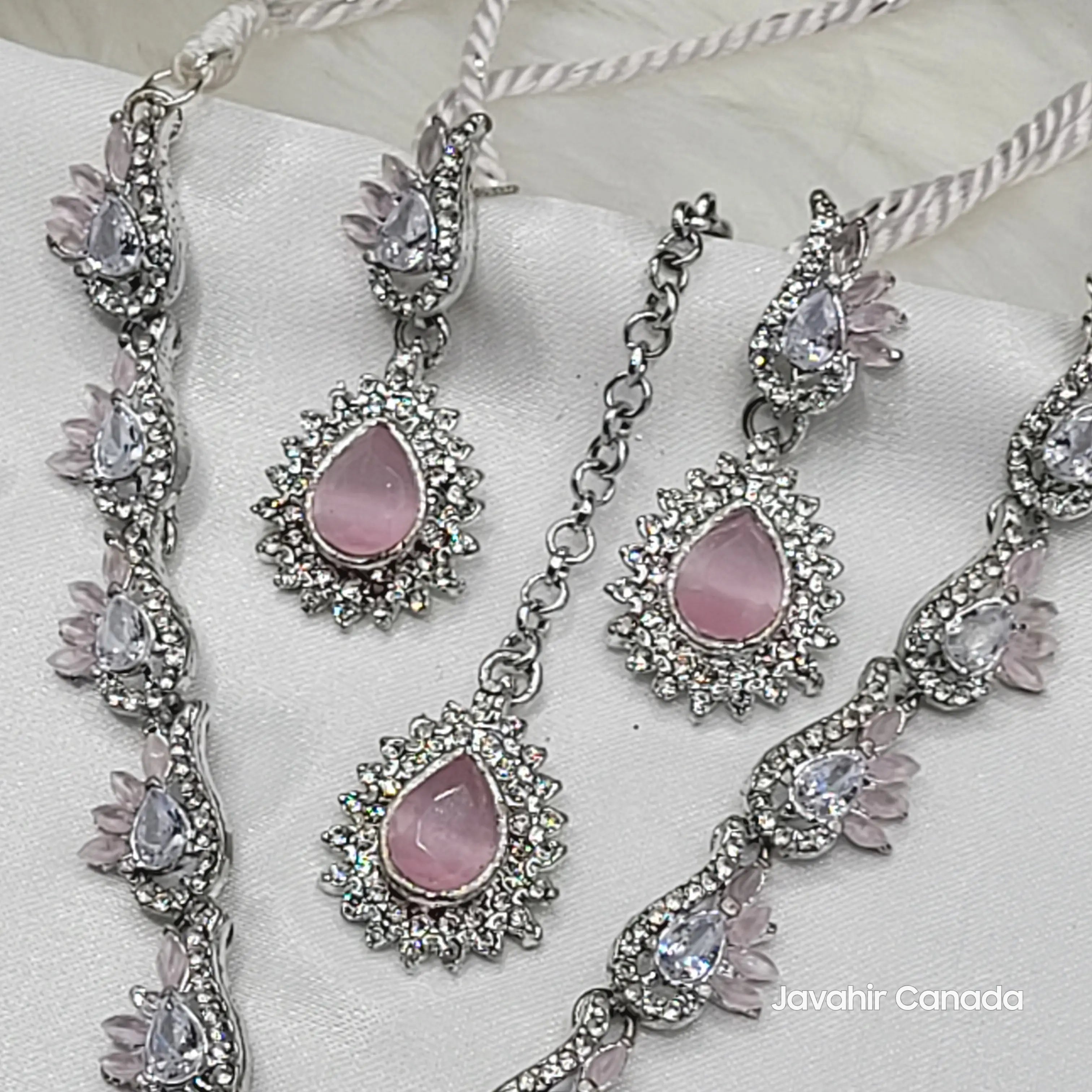 Jewelry set with pink stones and silver accents on a white fabric background