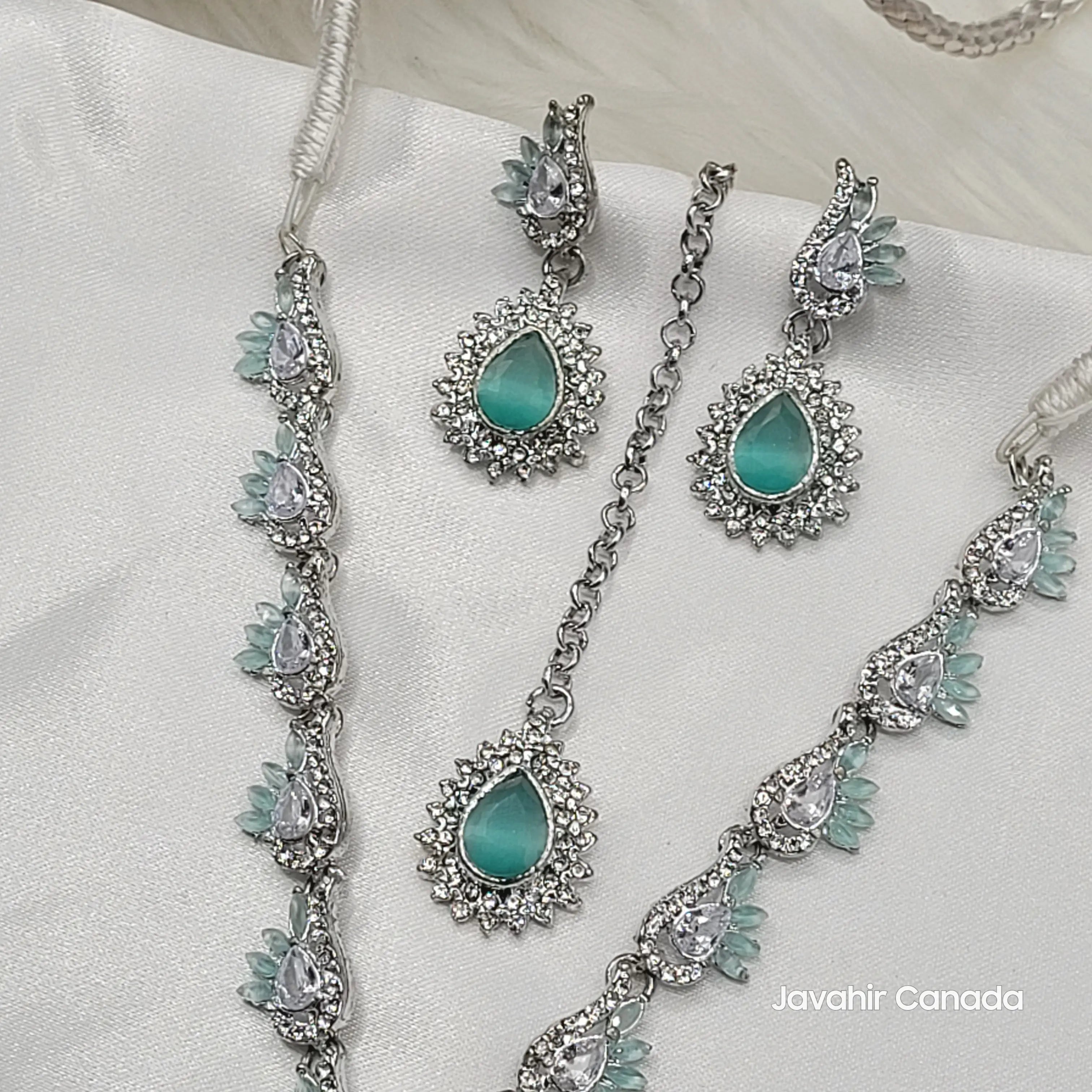 Jewelry set with turquoise stones and silver accents on a white fabric background, branded 'Javahir Canada'.