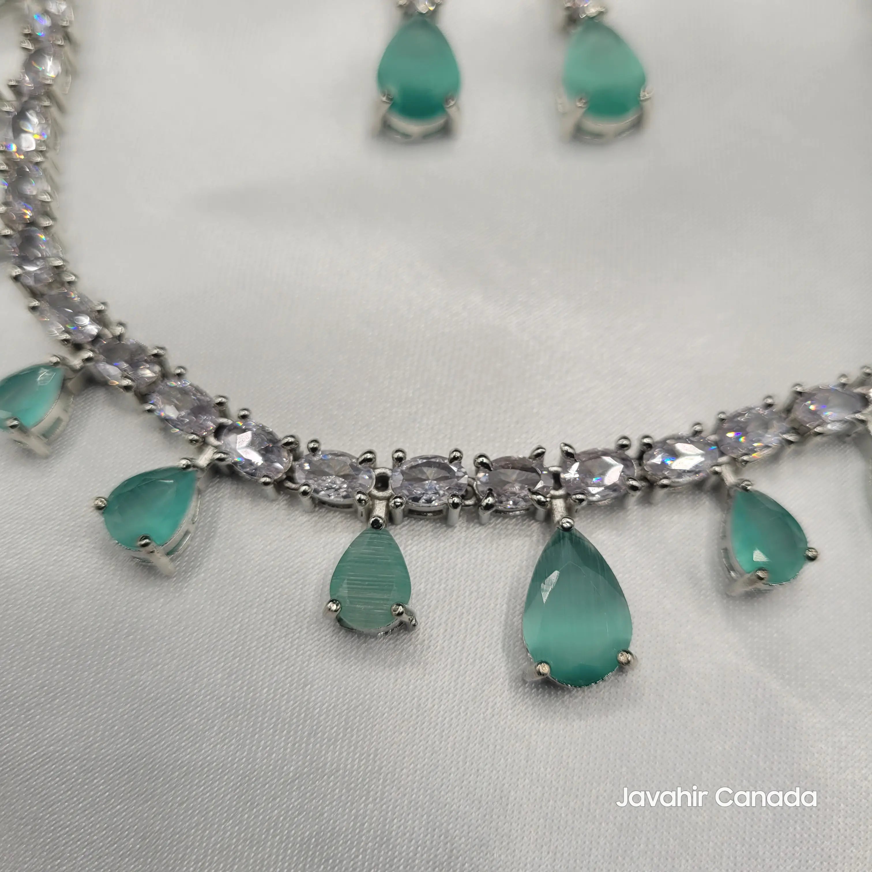 Zoomed view of JV145 mint green CZ necklace with large center teardrop stones on a light gray background.