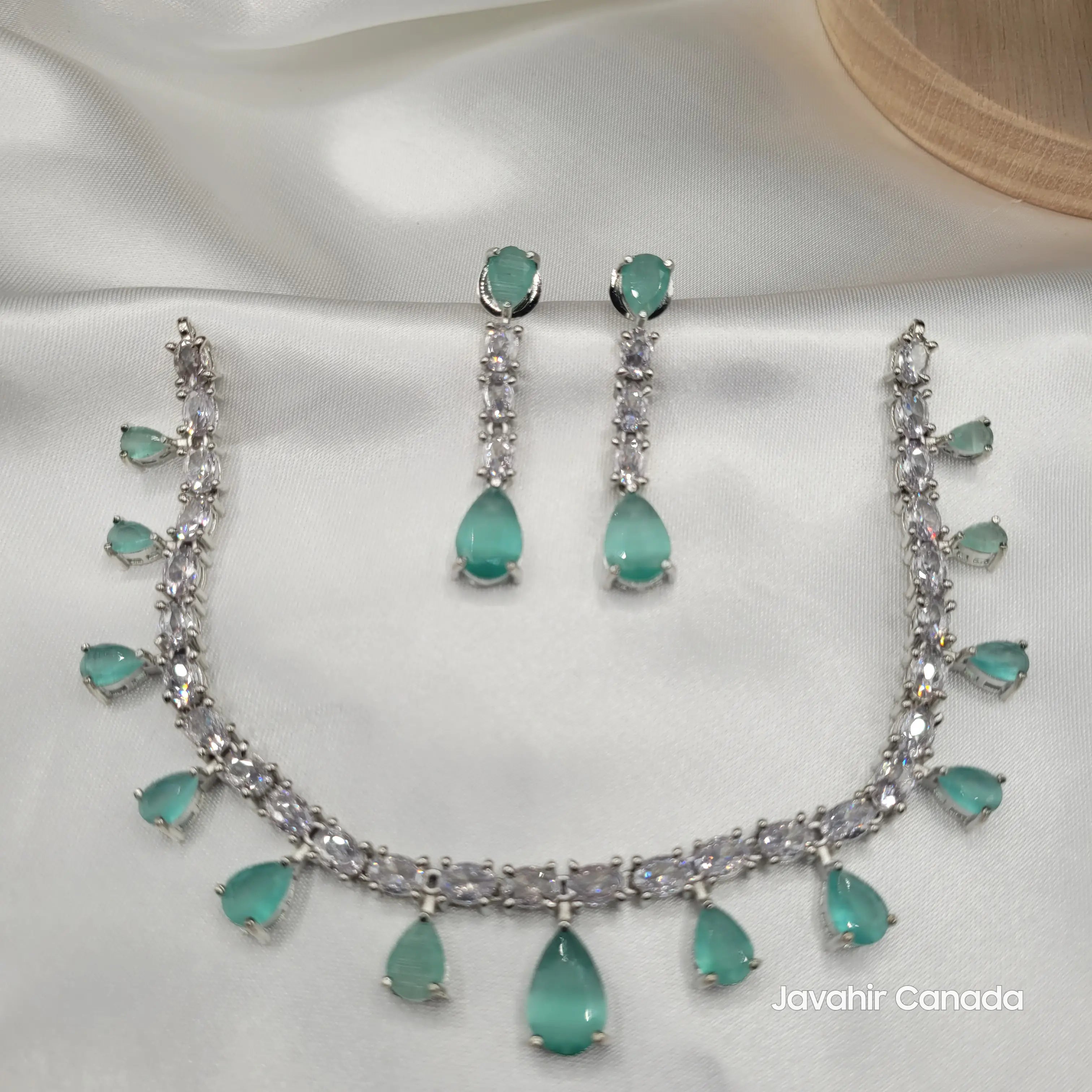 JV145 mint green CZ teardrop necklace and earring set laid out on satin for display.