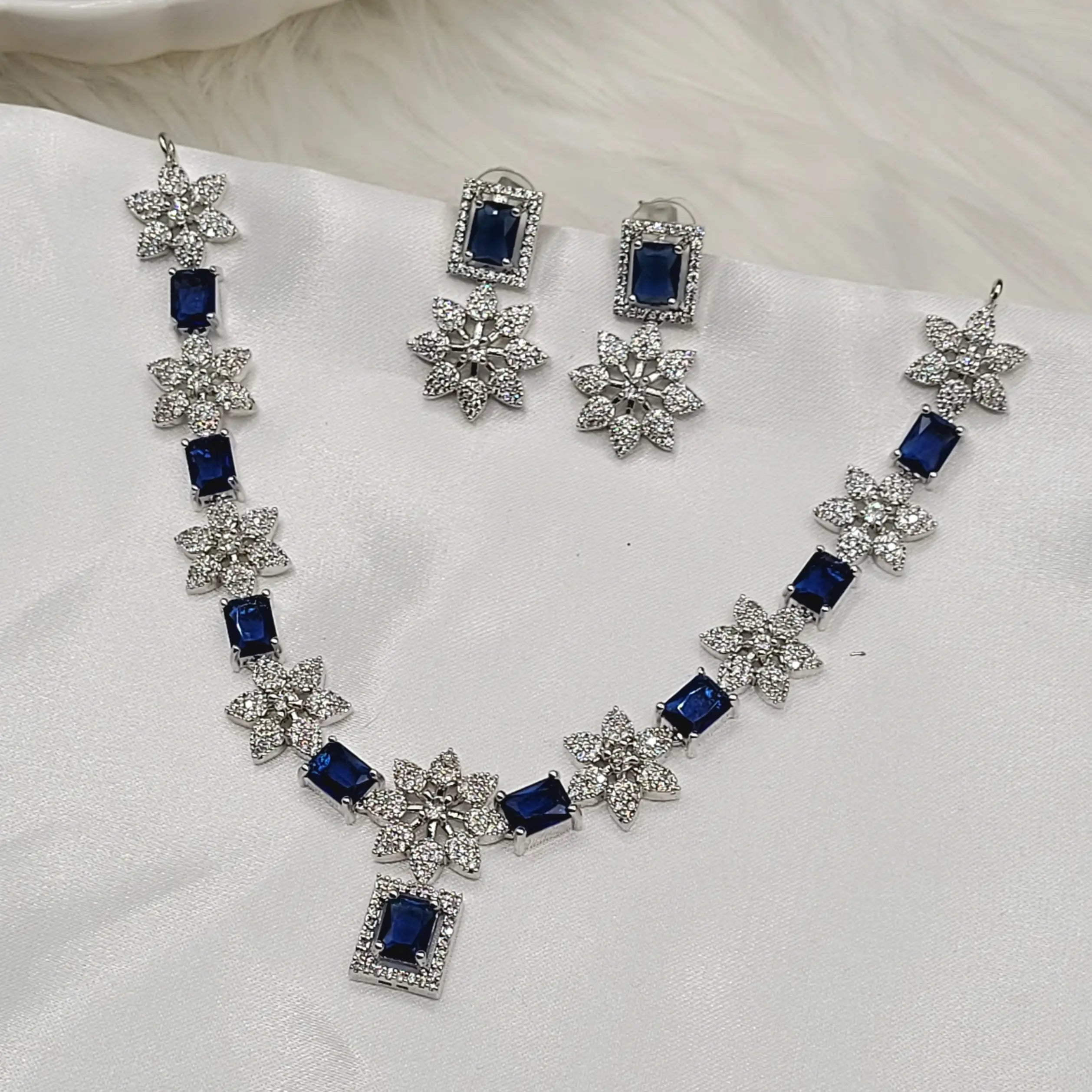 JV146 necklace set in sapphire blue CZ on silver base with floral design.